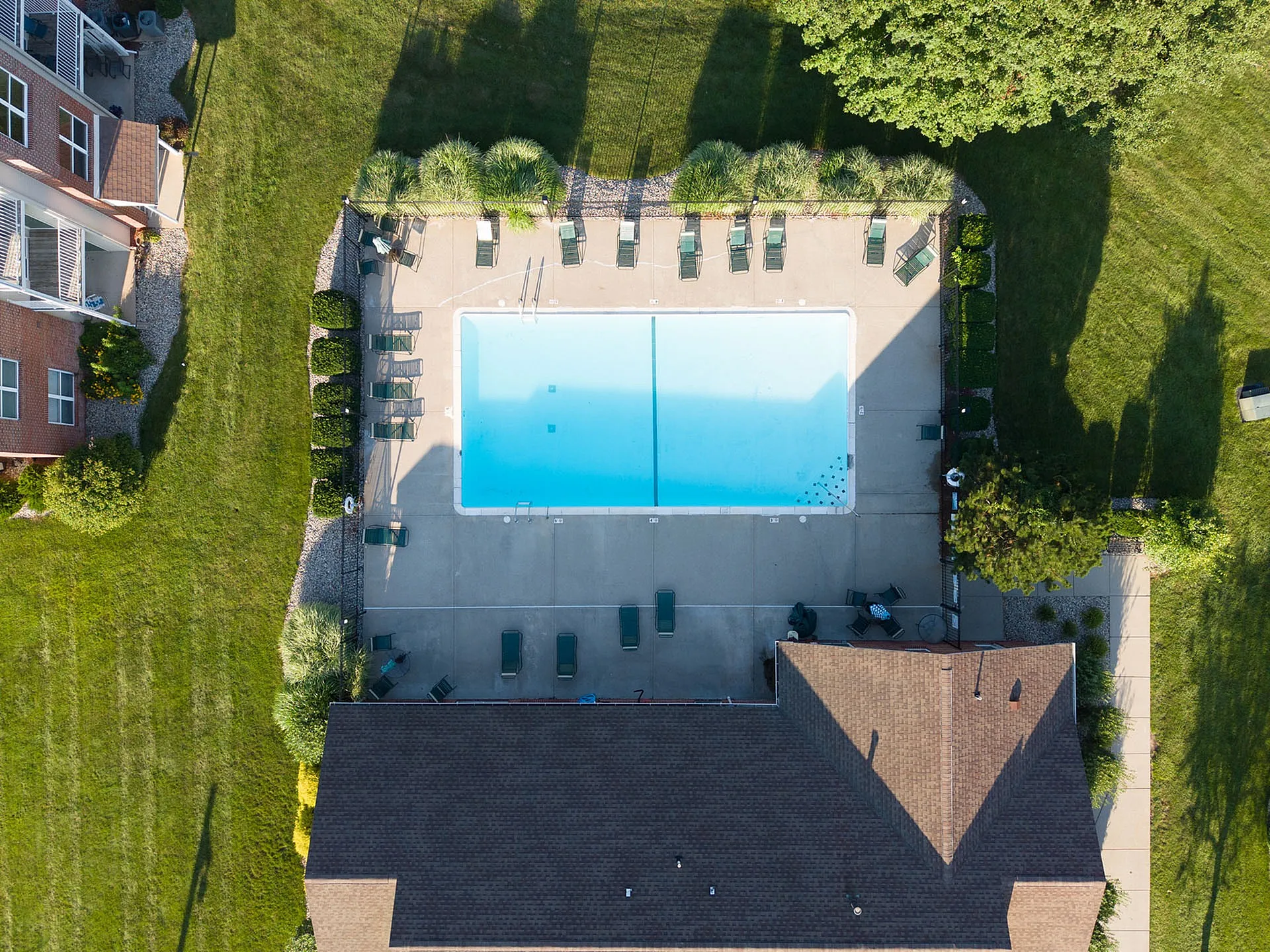 Aerial view of a serene outdoor pool area surrounded by lush greenery, perfect for relaxation and leisure.