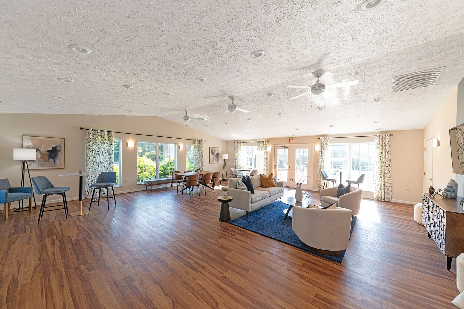 Bright and spacious living area with modern furnishings, hardwood floors, and large windows allowing natural light to flood in.