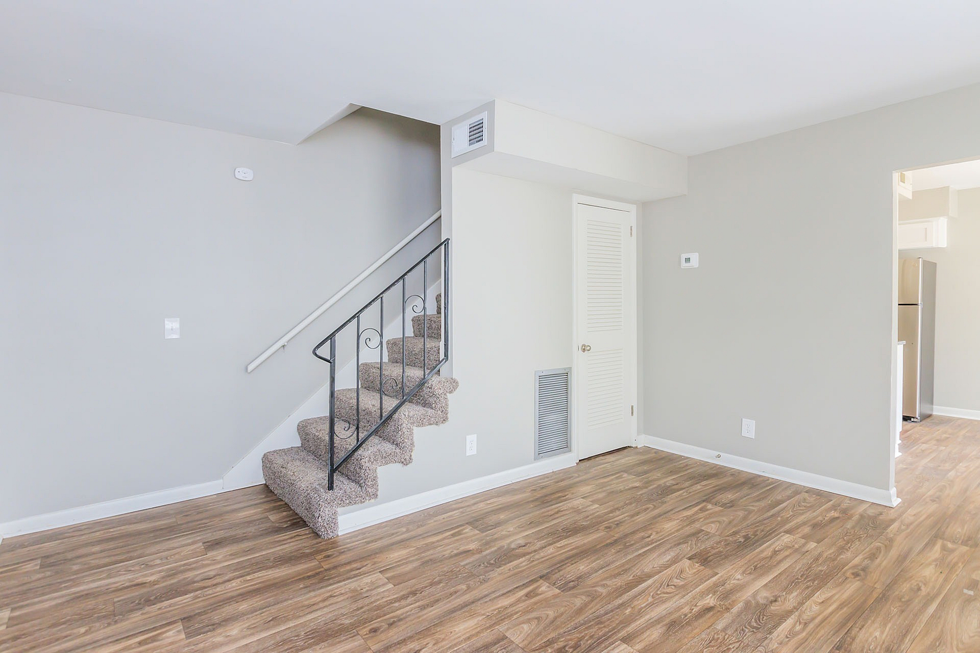 Bright, modern space featuring elegant hardwood floors and a chic, carpeted staircase leading to a contemporary upper level.