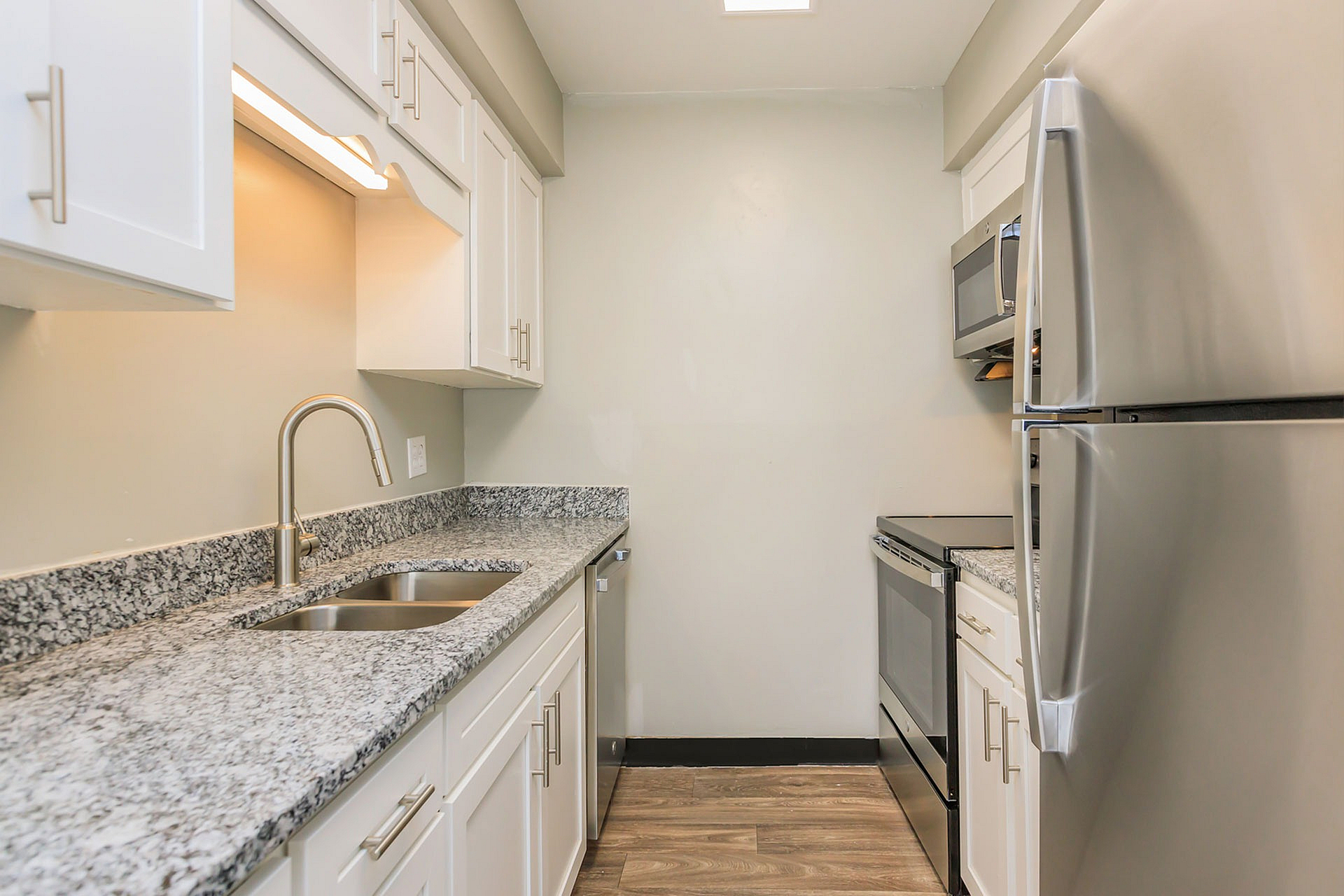 Modern kitchen with sleek granite countertops, stainless steel appliances, and stylish white cabinetry.