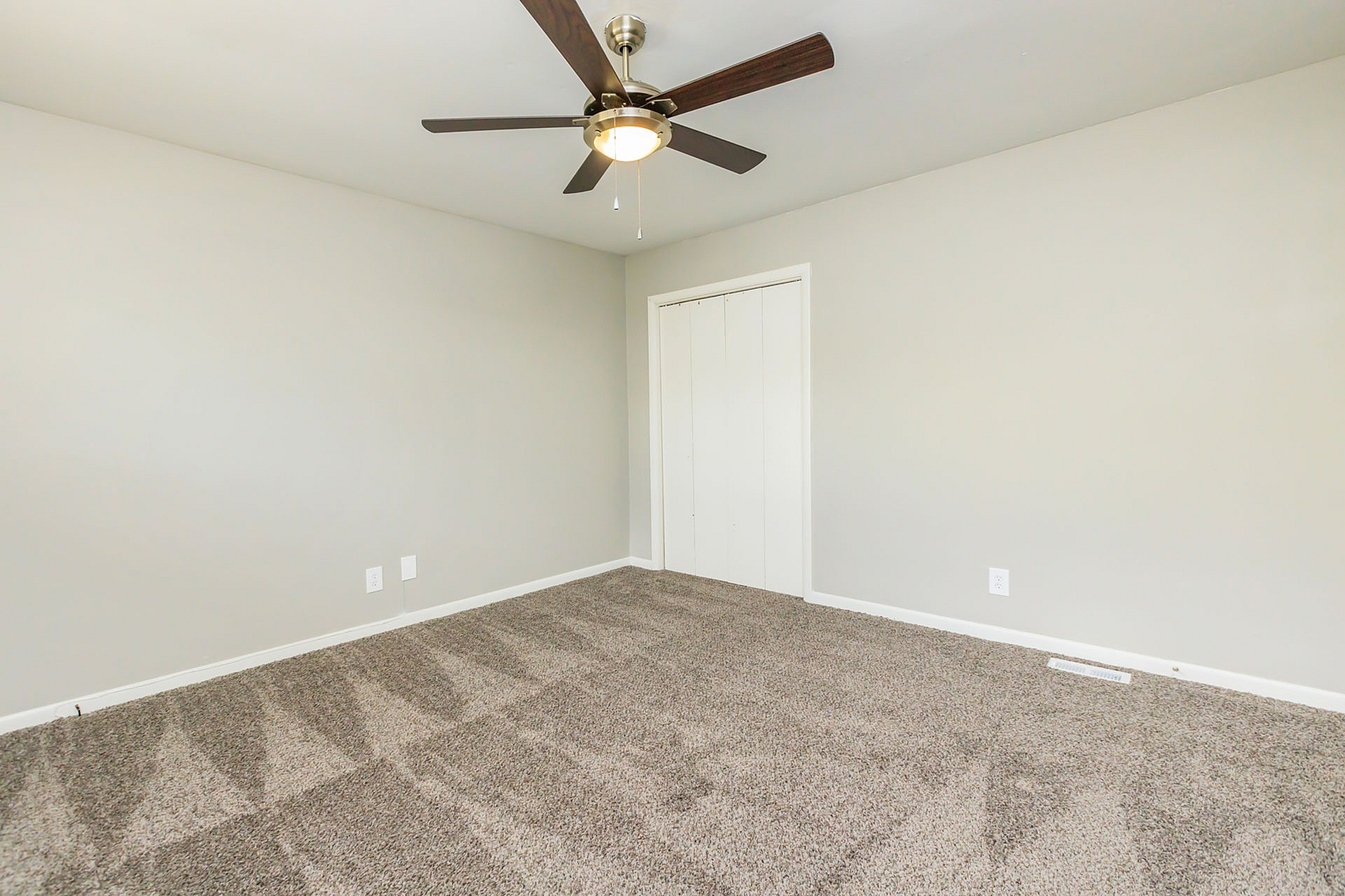Bright bedroom with plush carpeting, modern ceiling fan, and ample closet space, offering a cozy and comfortable living area.