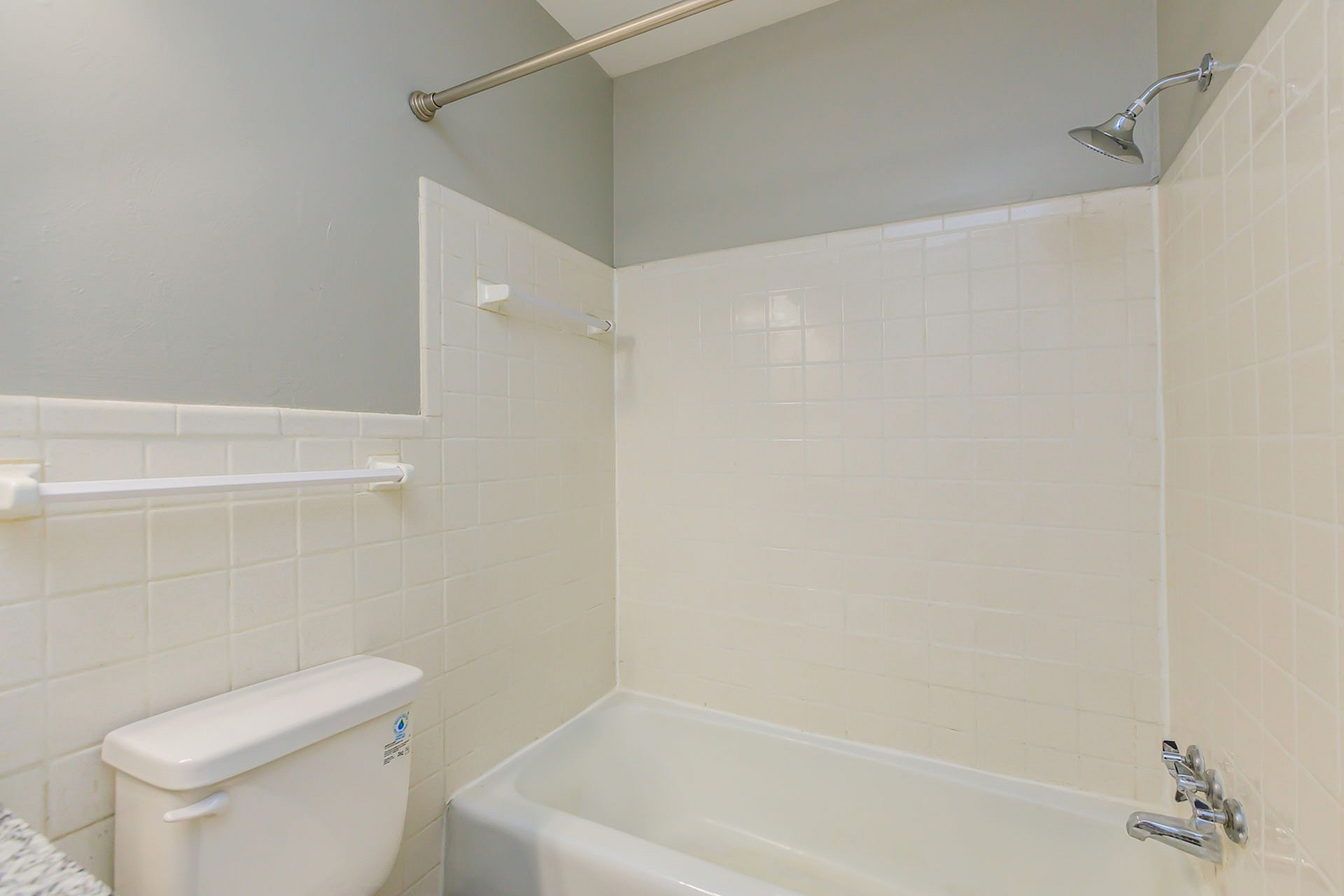 Bright and elegant bathroom featuring a pristine bathtub, white tiled walls, and modern fixtures.