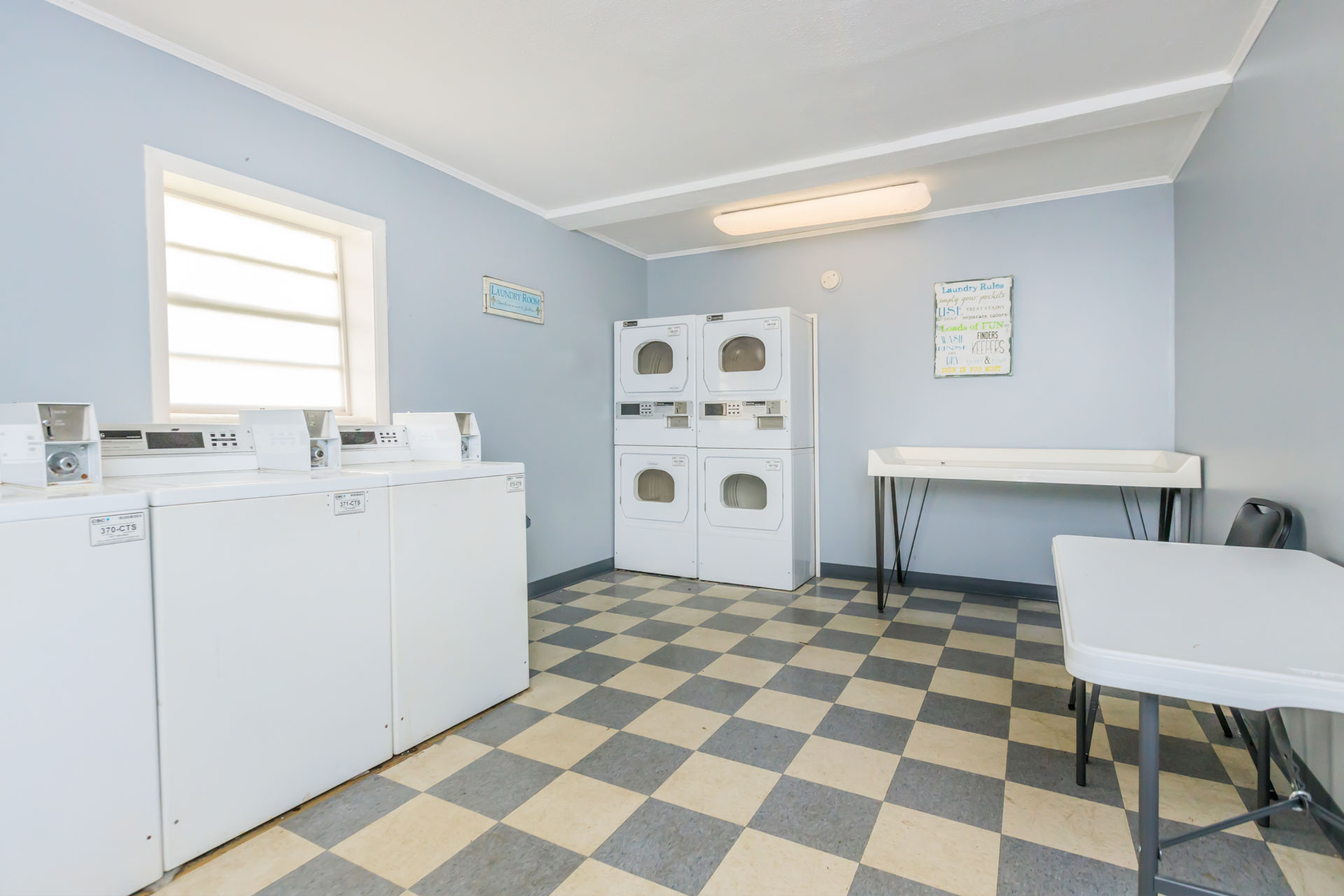 Bright and clean laundry room featuring multiple washers and dryers for convenient living.