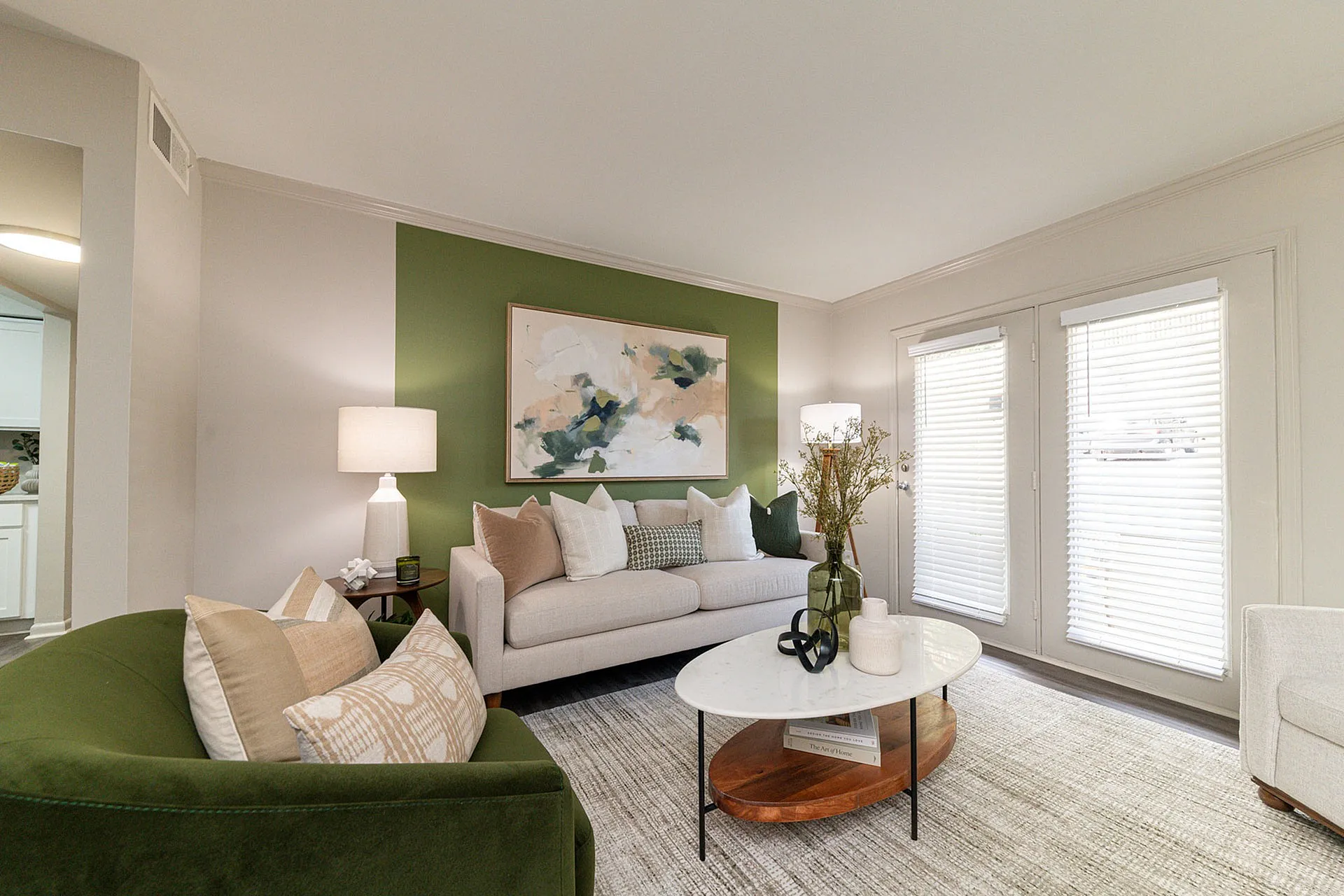 Elegant living room with modern decor, featuring a cozy sofa, vibrant green accent chair, abstract art, and a chic coffee table.