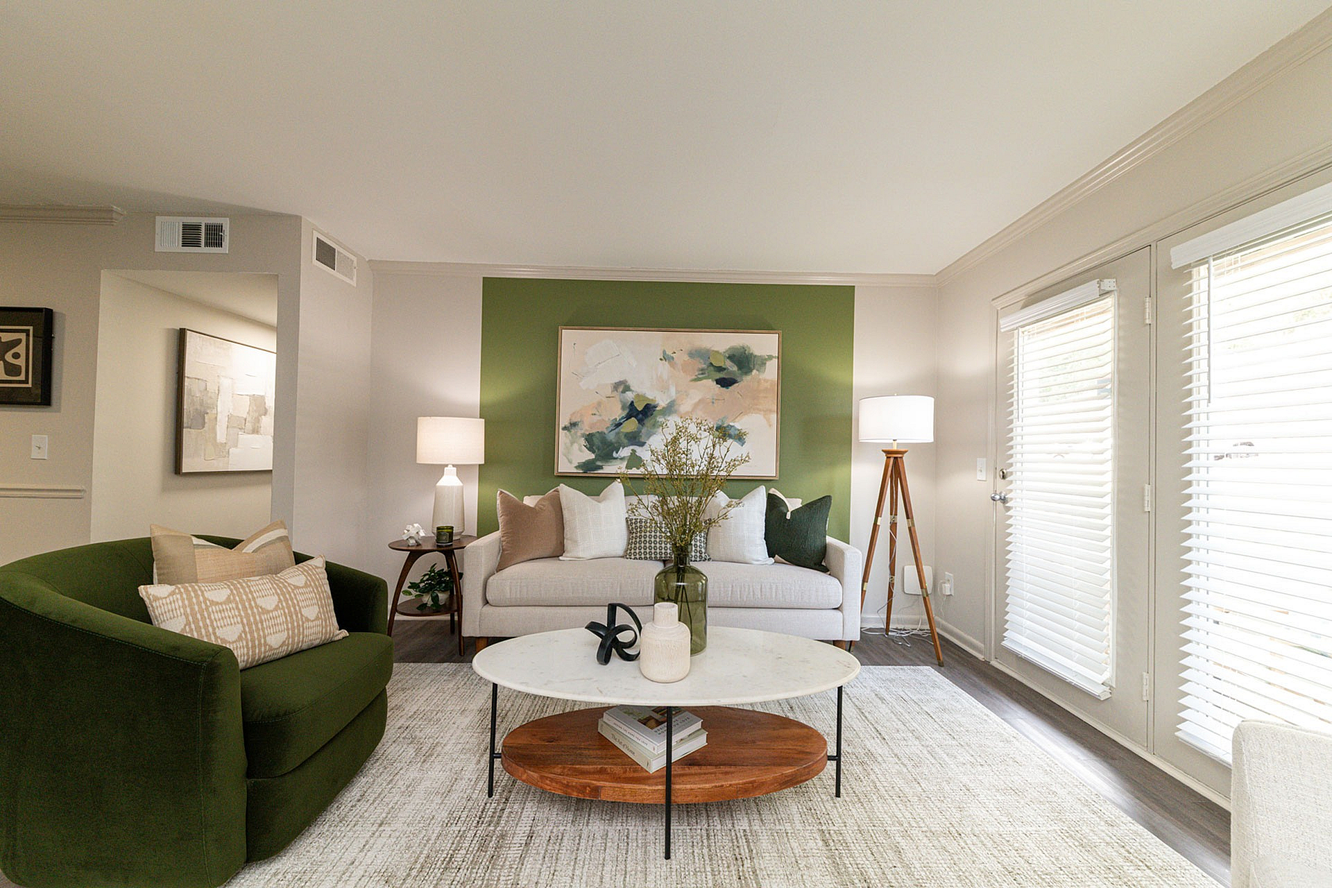 Bright and inviting living room with modern decor, featuring a stylish green accent wall, plush seating, elegant lighting, and a chic coffee table.