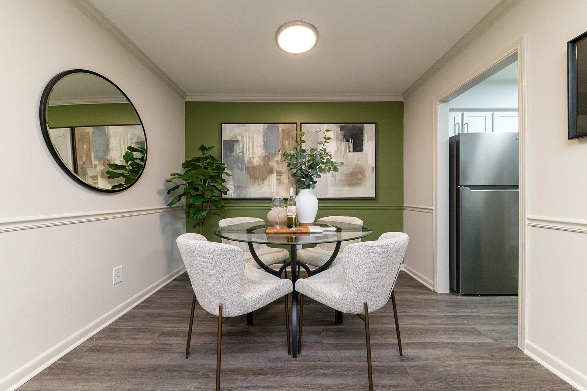 Chic dining area with stylish round glass table, elegant decor, and a vibrant green accent wall.