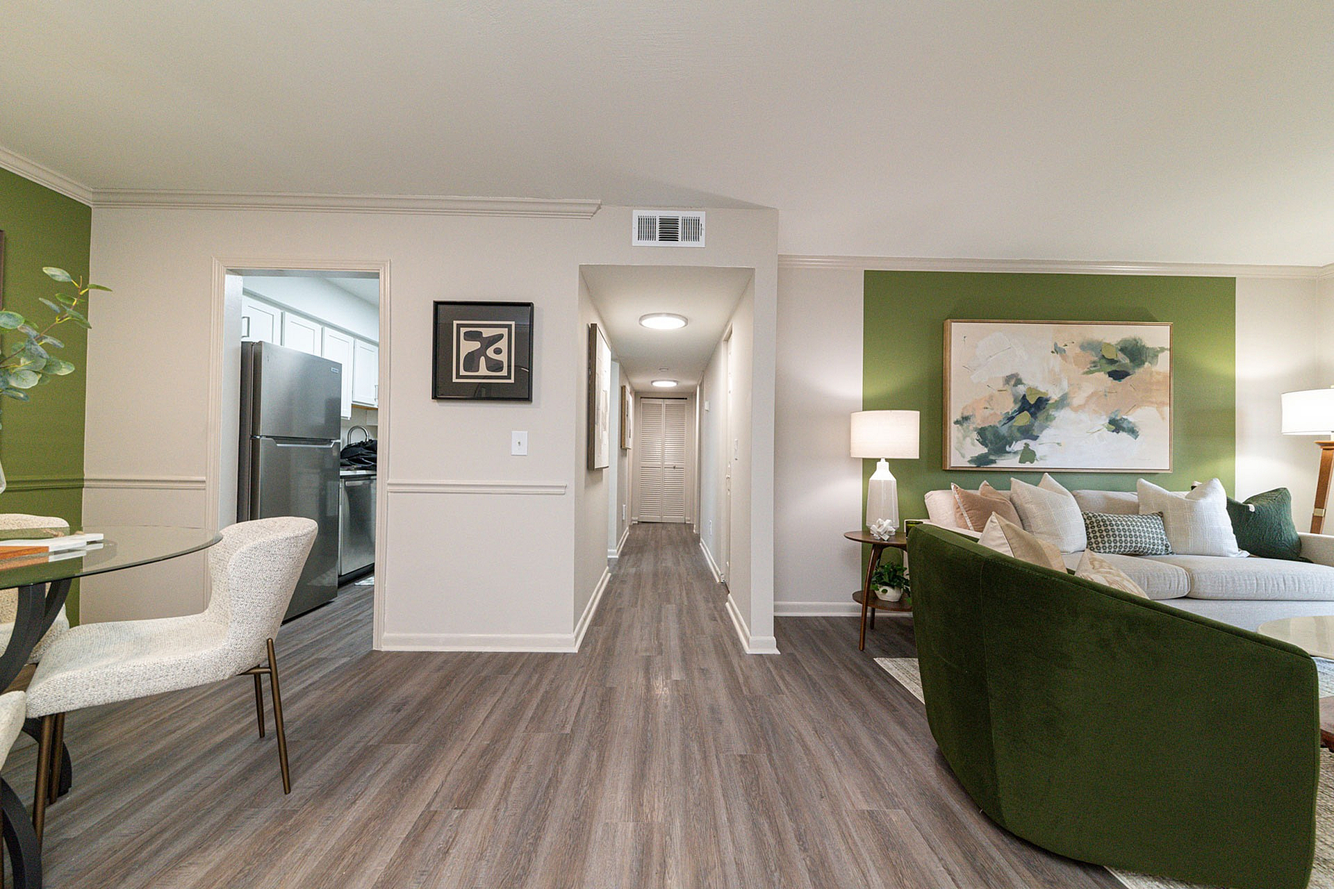 Modern apartment living area with elegant decor, featuring a cozy sofa, stylish artwork, and a welcoming open layout with a glimpse of the sleek kitchen.
