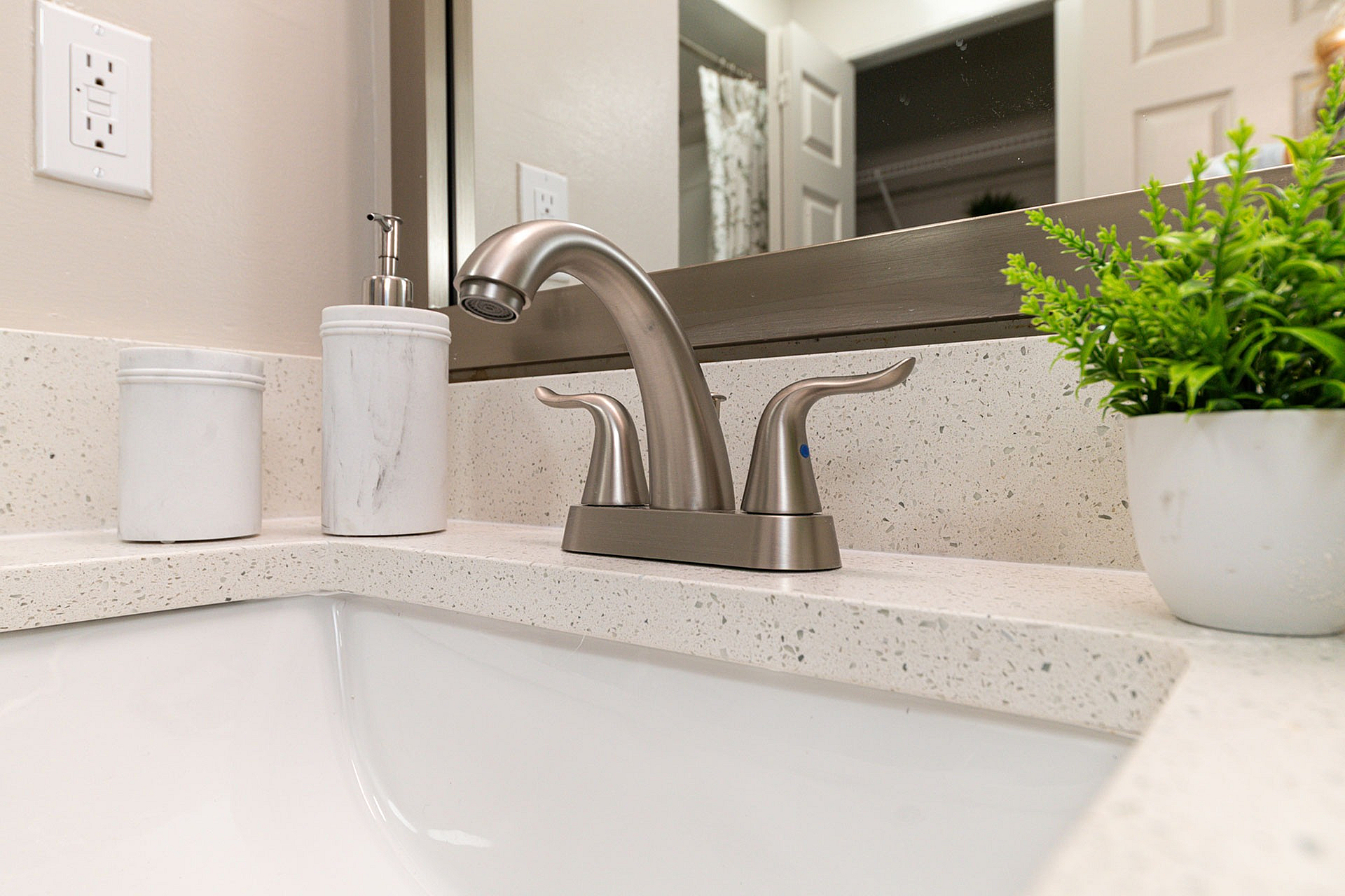 Elegant bathroom detail showcasing a modern brushed nickel faucet, stylish beige countertop, and chic decor elements in a sophisticated apartment.