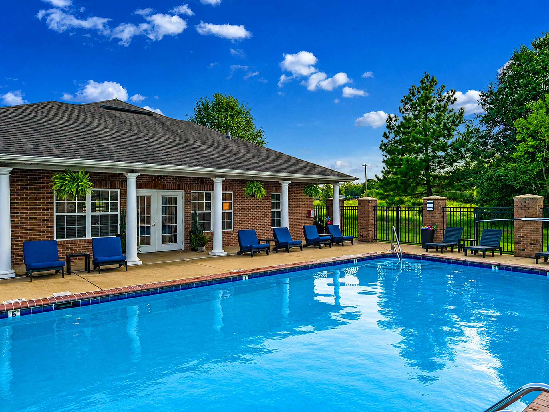 Charming outdoor pool area with comfortable lounge chairs and lush landscaping, perfect for relaxation.
