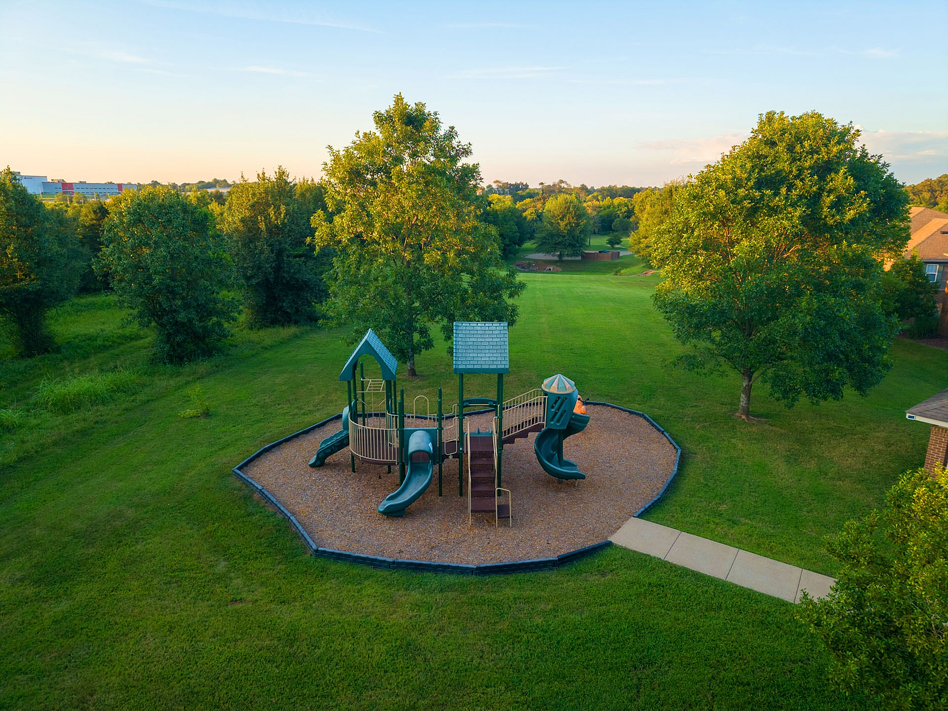 Charming community park with a modern playground set amidst lush greenery, perfect for family fun and relaxation.