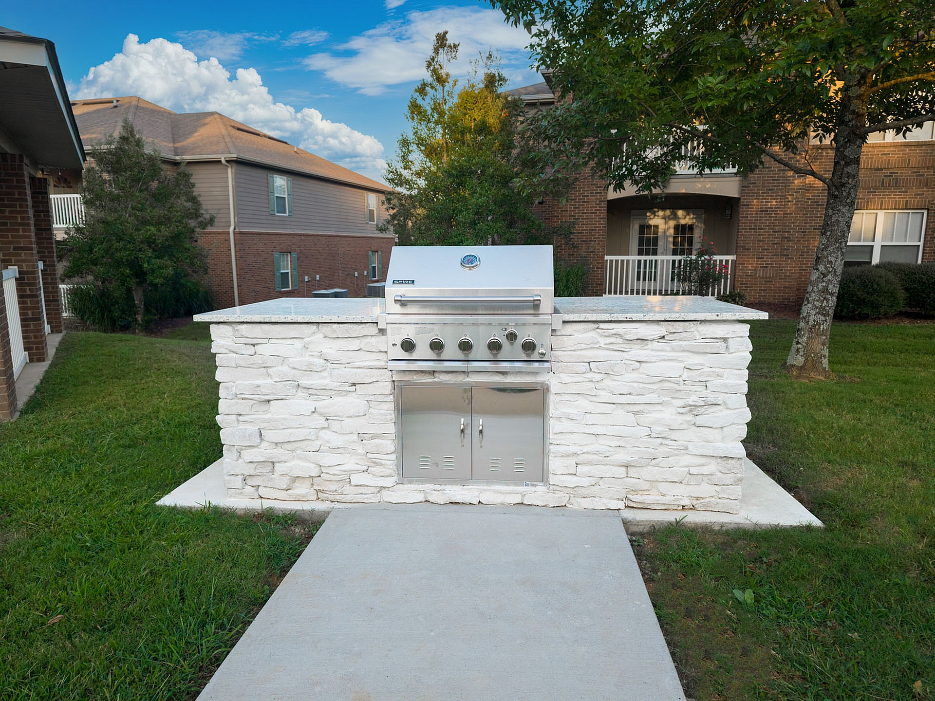 Charming outdoor BBQ grill setup with a stylish stone finish, perfect for entertaining in a serene apartment community setting.
