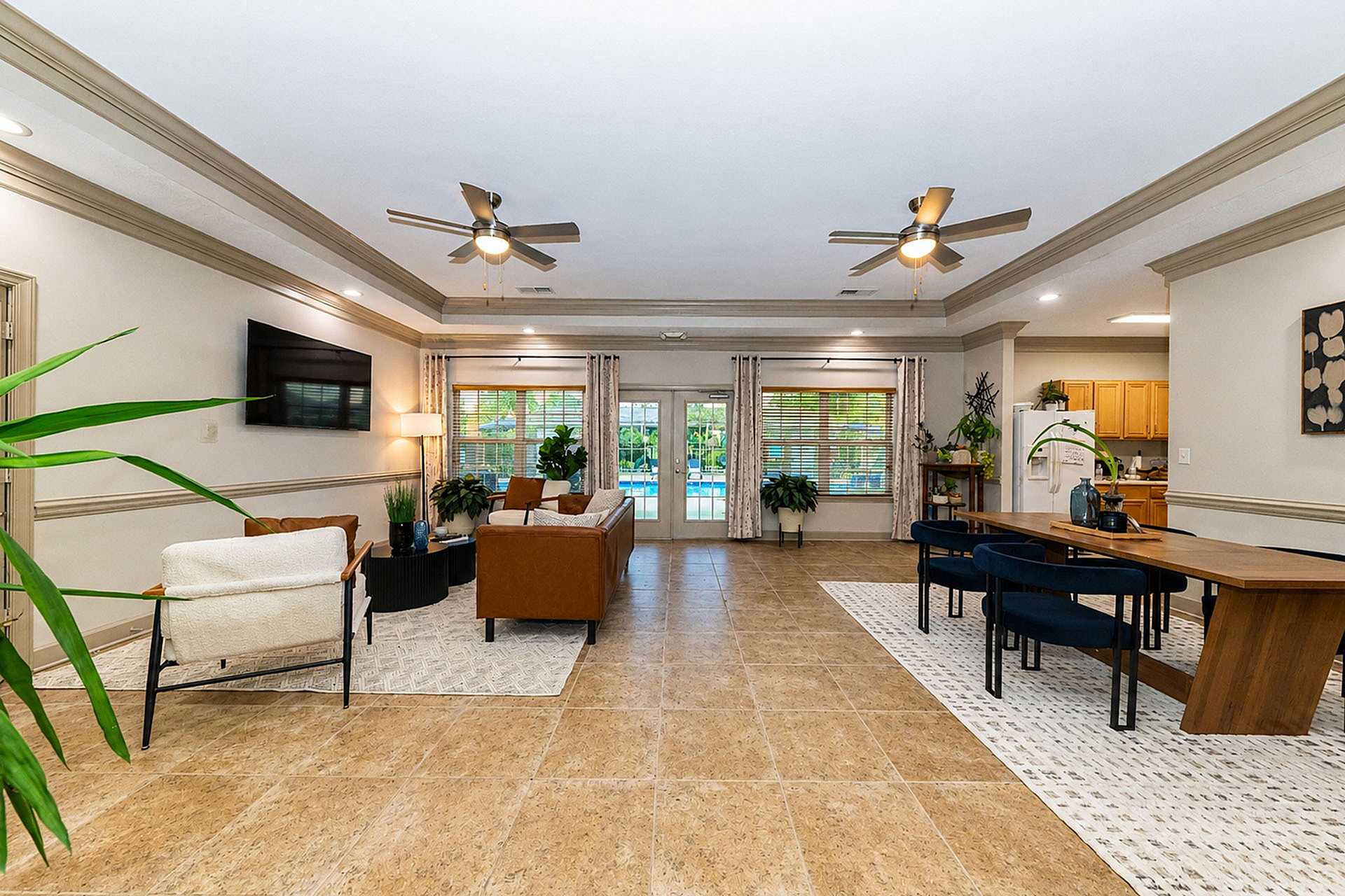 Spacious open-plan living area with stylish decor, wooden dining table, and plush seating, enhanced by vibrant greenery and natural light.