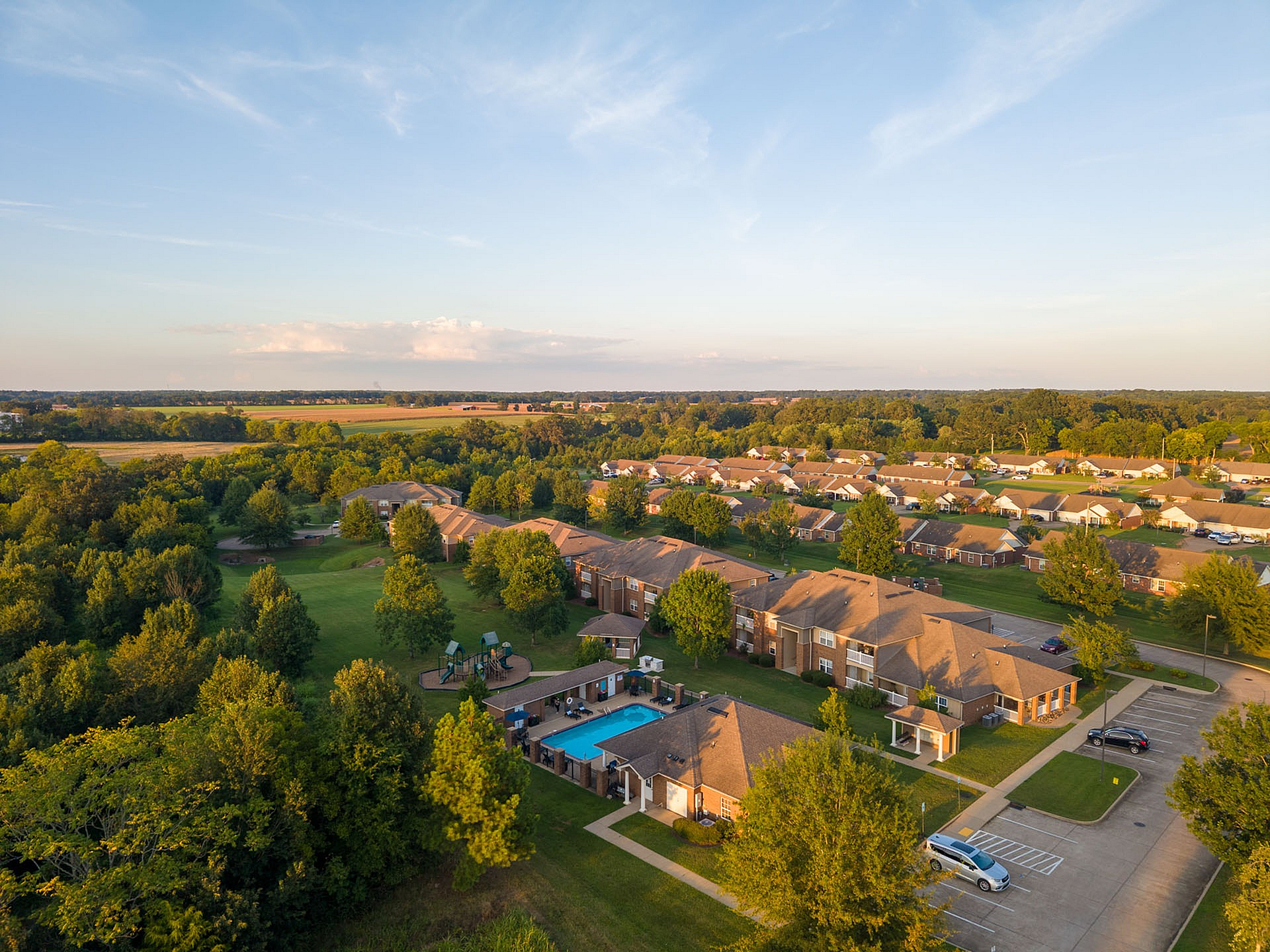 Scenic aerial view of a charming suburban neighborhood featuring lush greenery, modern townhouses, and a refreshing community pool.