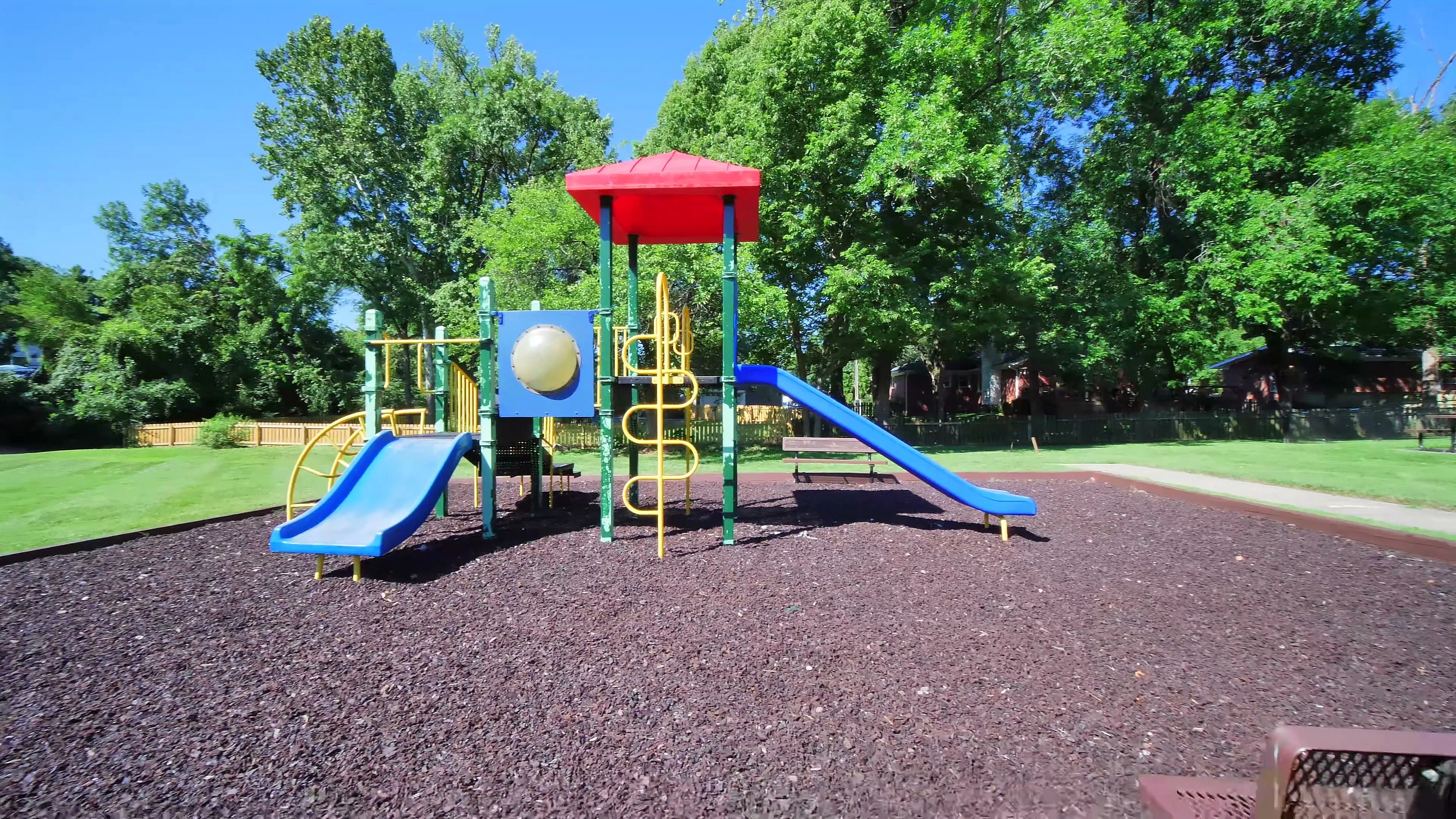 Vibrant playground with colorful slides and climbing structures surrounded by lush greenery, perfect for family fun.
