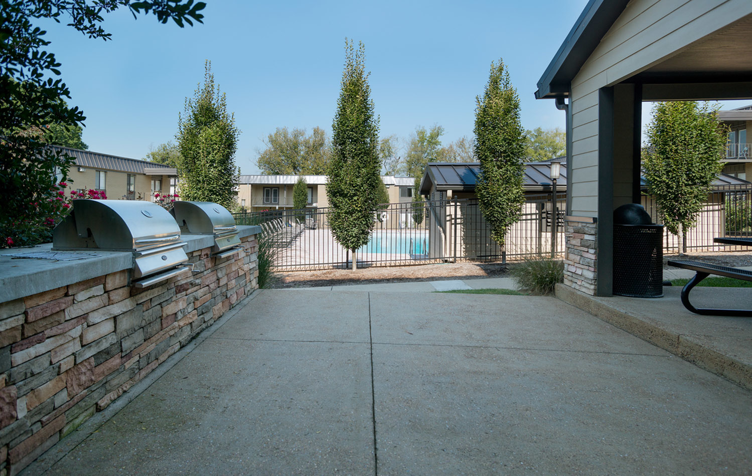 Charming outdoor patio with modern grill setup and lush landscaping.