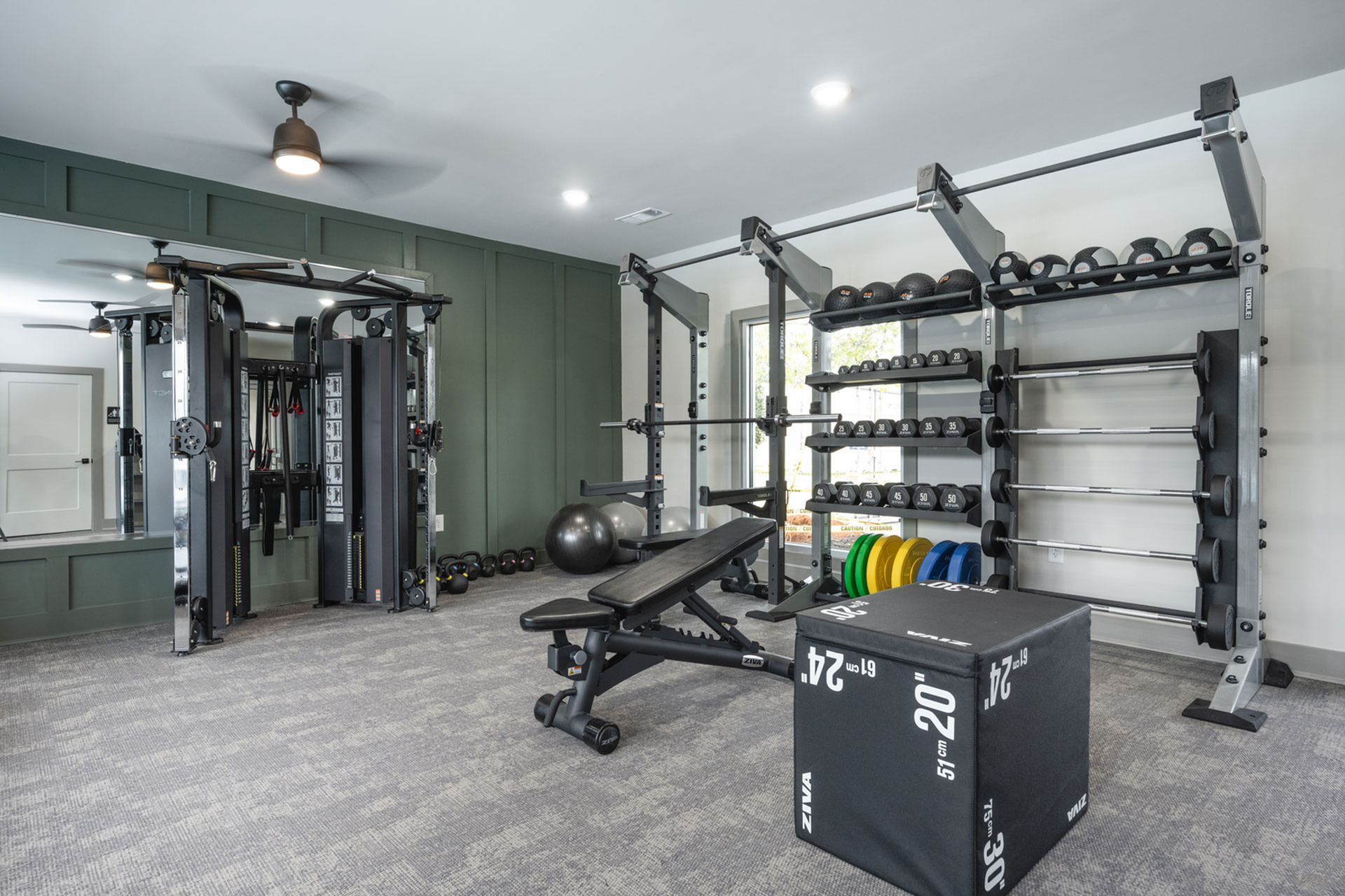 Modern apartment fitness center with diverse equipment including weights, benches, and training machines, perfect for an active lifestyle.