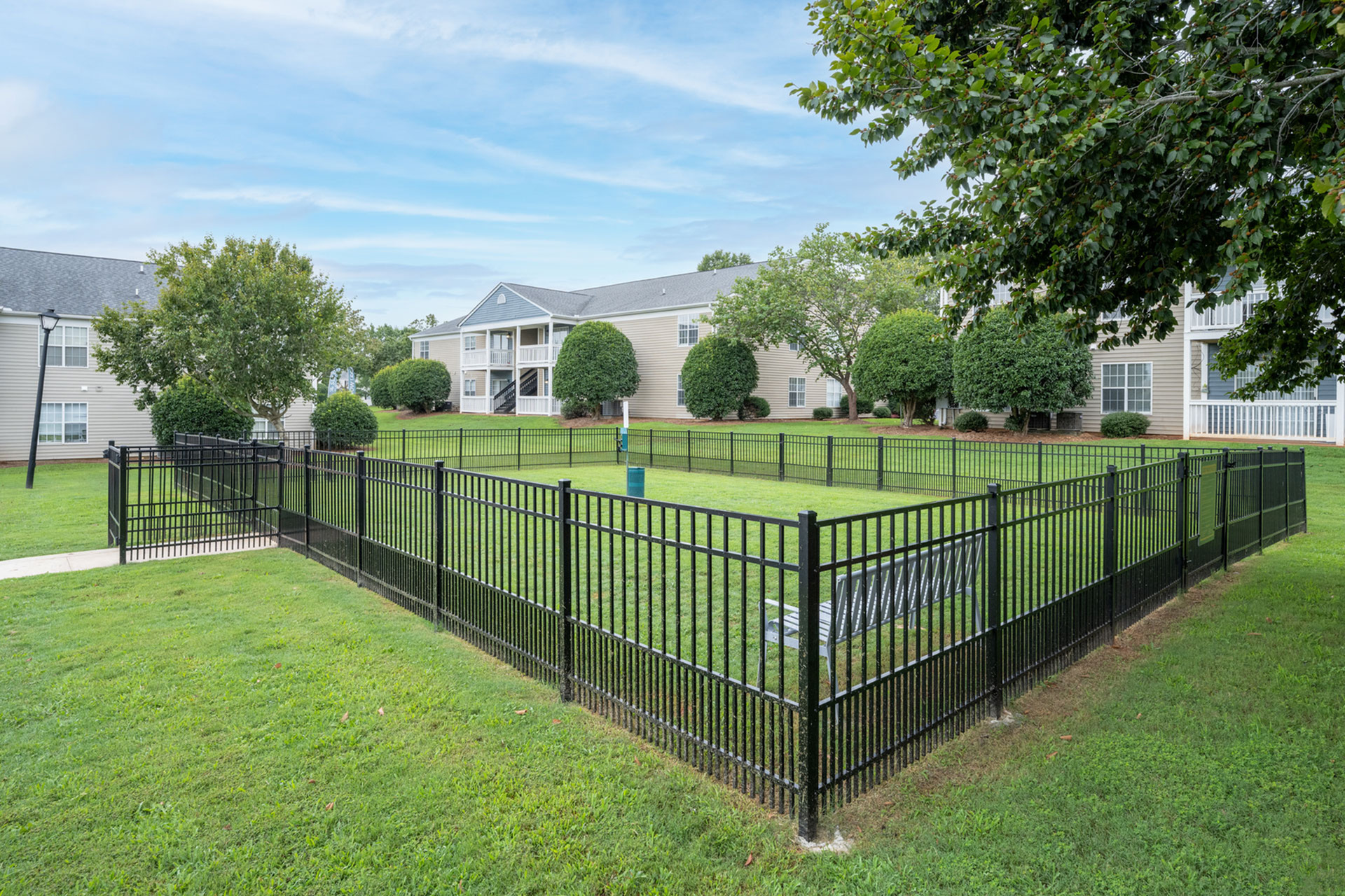 Charming apartment community with lush green landscapes and modern fencing, offering a serene and inviting atmosphere.