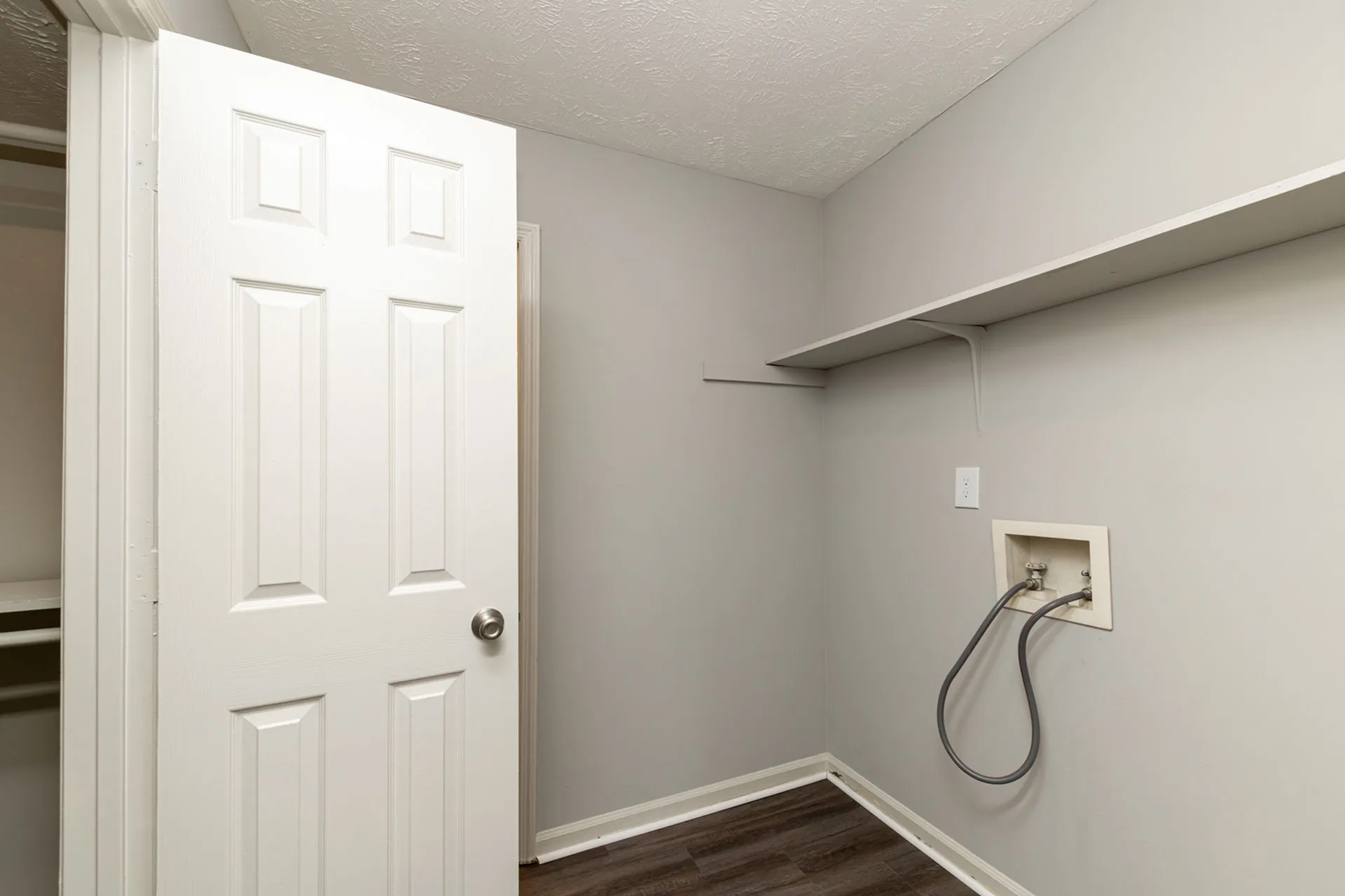 Bright utility room with modern fixtures, spacious shelving, and elegant wood flooring.