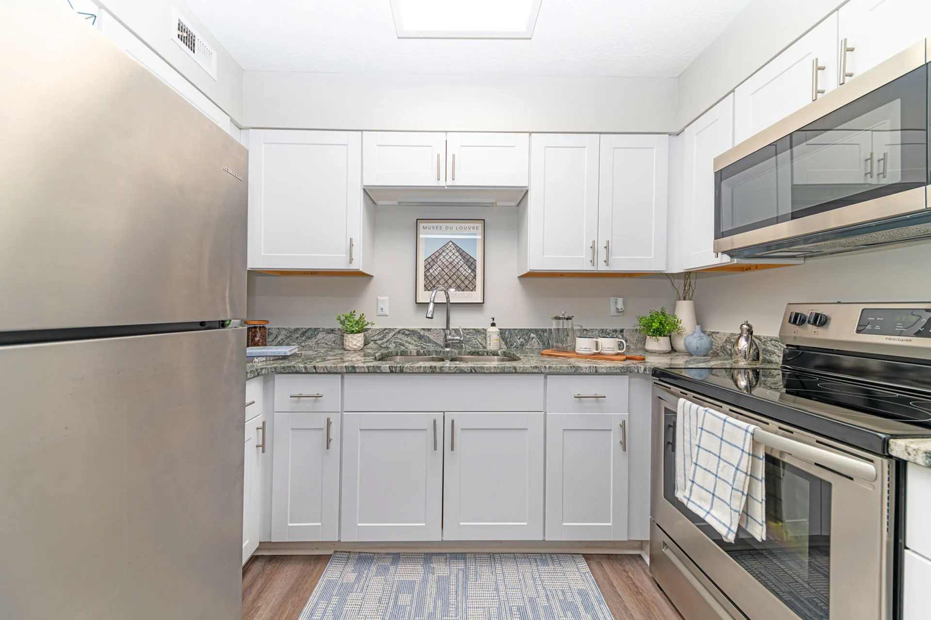 Modern kitchen with sleek stainless steel appliances, elegant white cabinetry, and stylish granite countertops, perfect for culinary creativity.