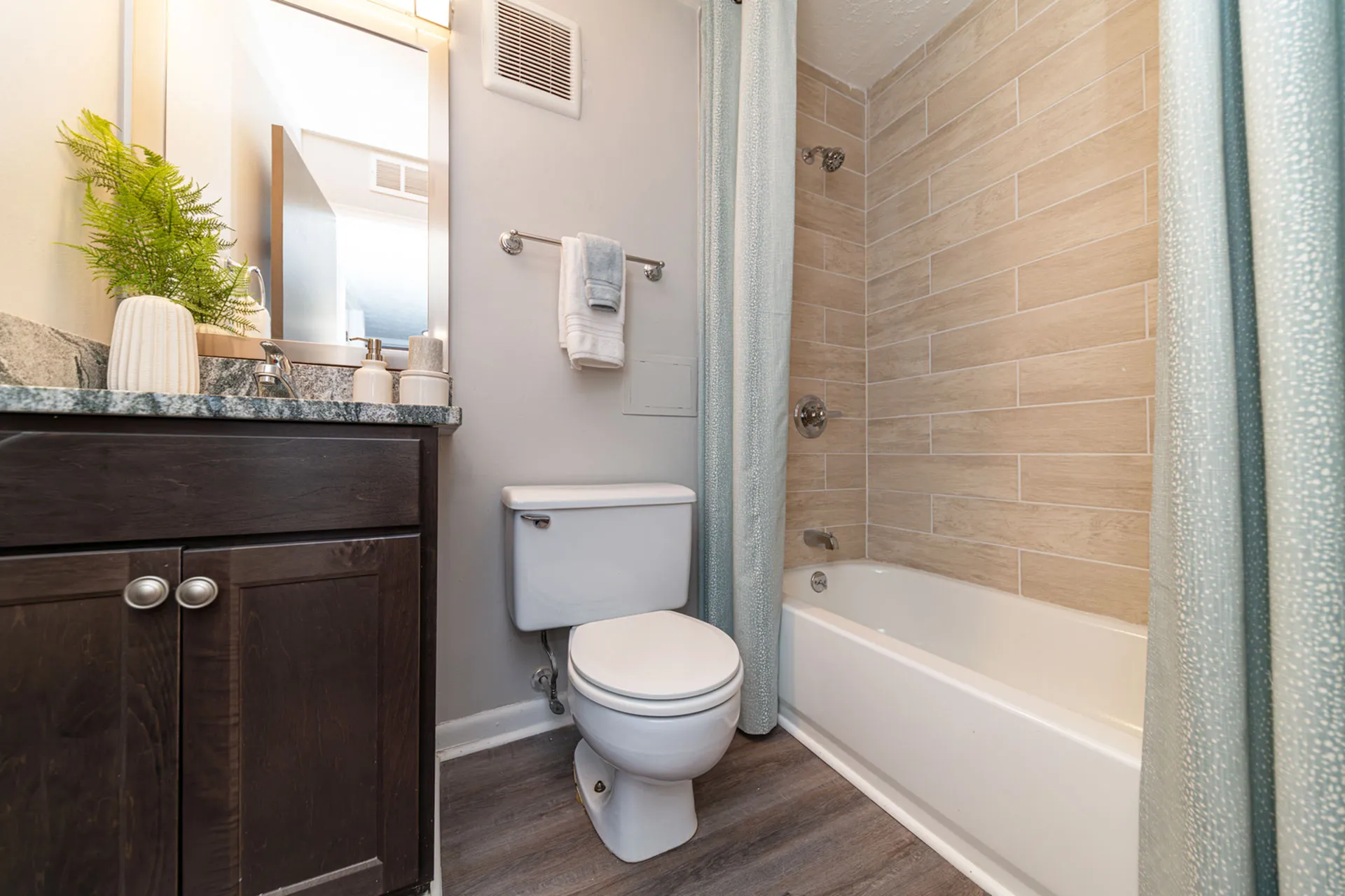 Elegant bathroom with modern fixtures, featuring a sleek granite countertop, chic wood cabinetry, and a stylish tiled shower.