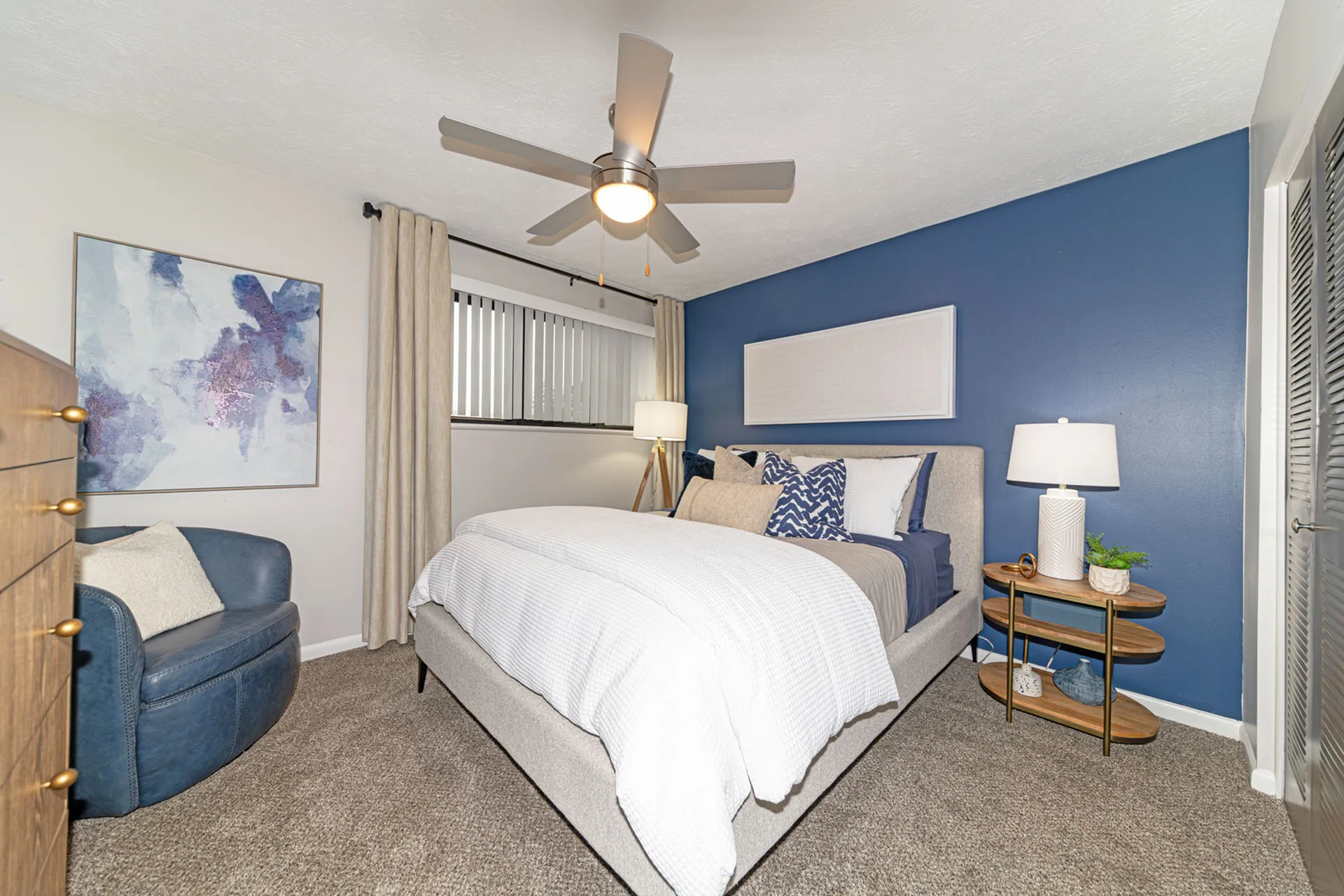Modern bedroom with a plush bed, vibrant blue accent wall, and elegant decor, creating a cozy and inviting atmosphere.