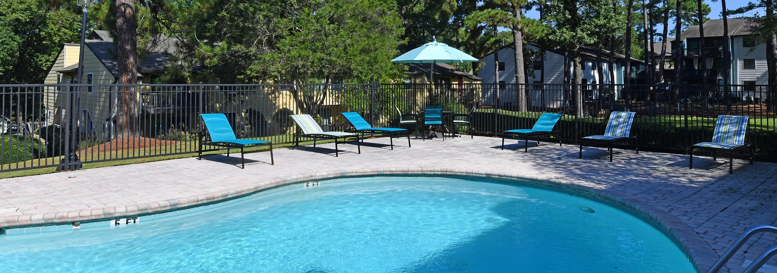Serene outdoor pool area with lounge chairs and surrounding greenery.