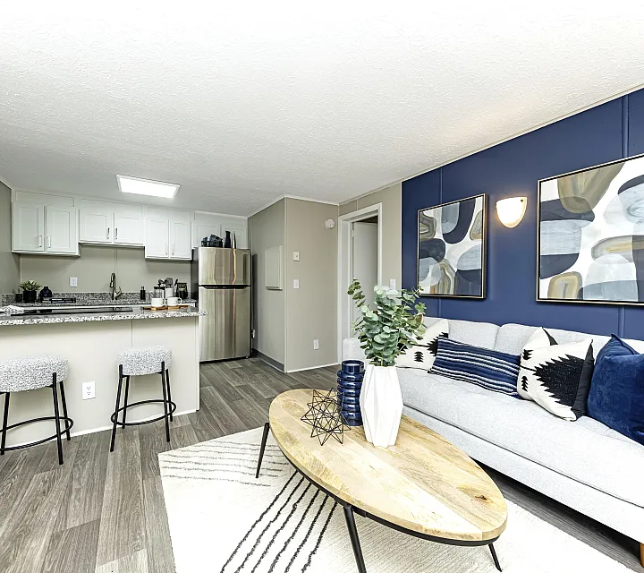 Elegant open-plan living area with stylish decor, featuring a cozy sofa, abstract wall art, and a modern kitchen with a breakfast bar.