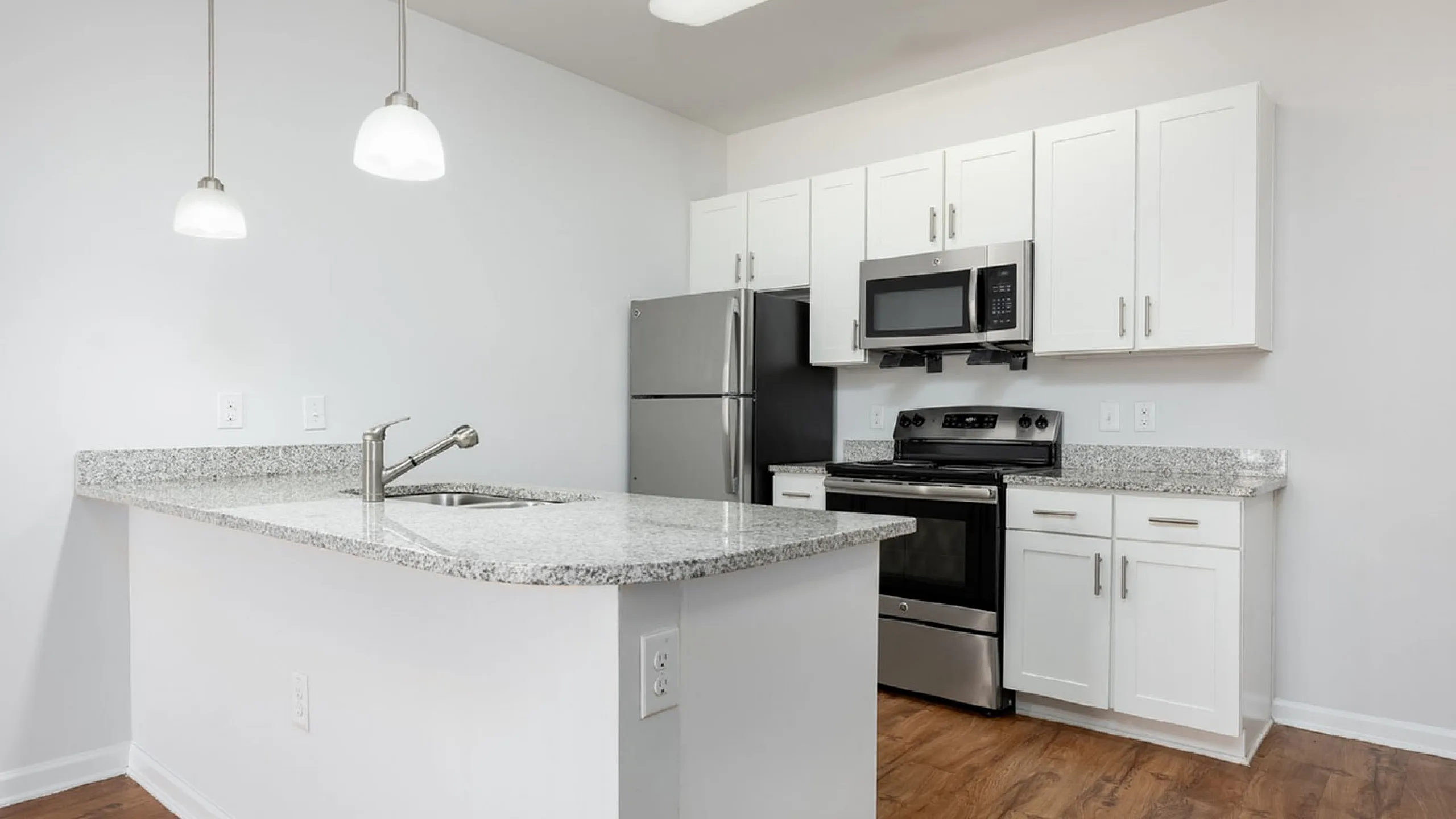 Modern kitchen with sleek granite countertops, stainless steel appliances, and elegant pendant lighting.