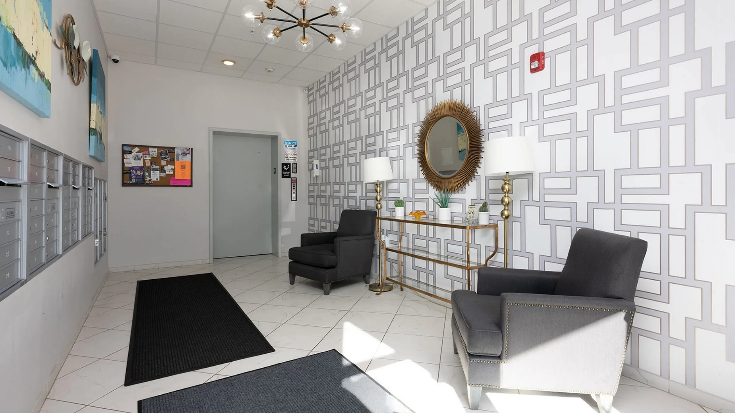 Elegant apartment lobby with modern decor, featuring stylish seating, geometric patterned wallpaper, and chic lighting.