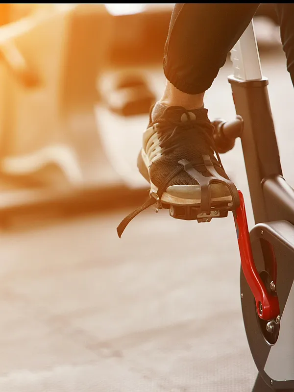Dynamic gym scene with a person energetically cycling on a modern exercise bike, basking in warm sunlight.