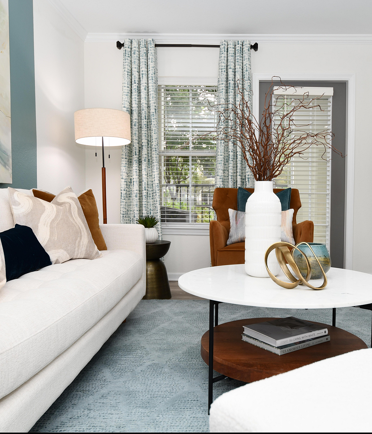 Elegant living room with a modern white sofa, cozy pillows, stylish round coffee table, and vibrant plant decor, creating a welcoming and chic atmosphere.