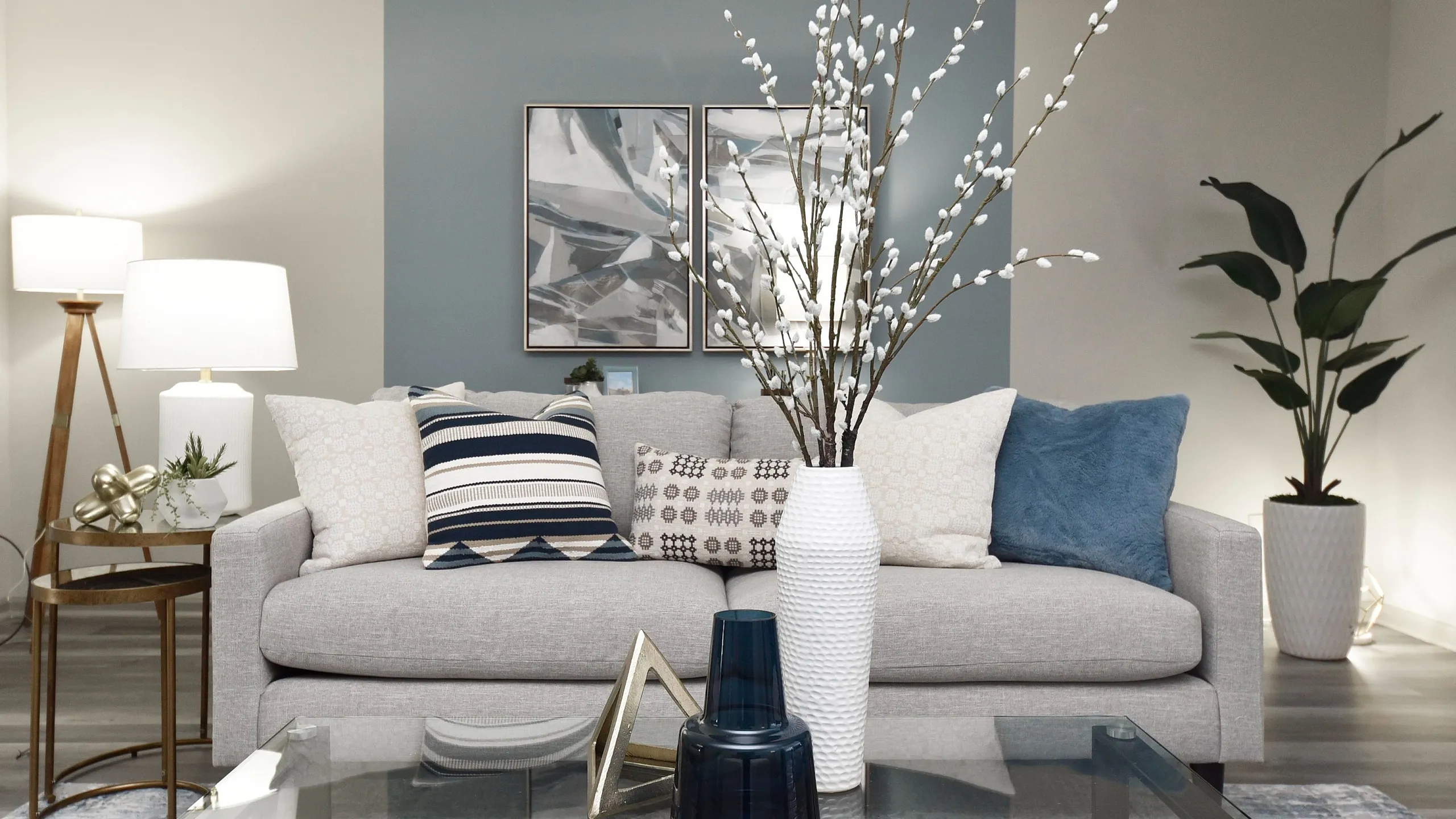 Chic living room with modern decor, featuring a plush gray sofa, elegant pillows, stylish artwork, and sophisticated lighting.