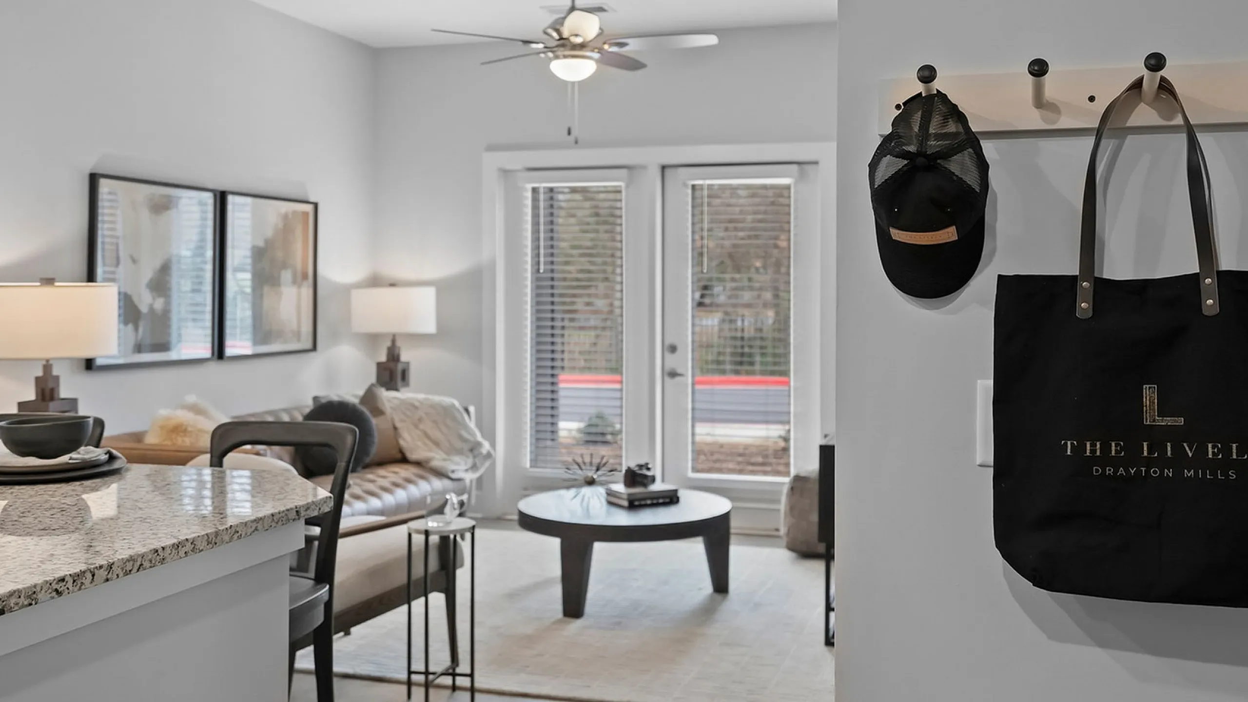 Modern apartment living room with elegant decor, featuring a cozy beige sofa, stylish artwork, and a granite breakfast bar under soft lighting.