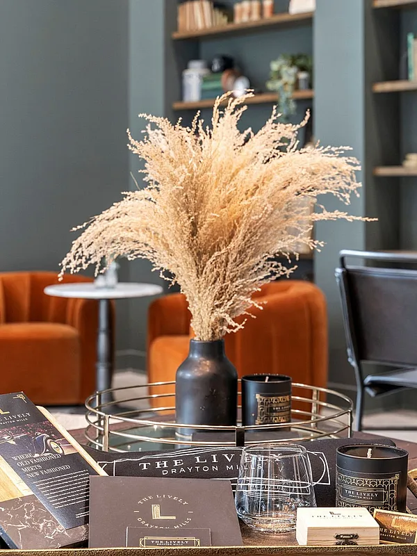 Inviting modern living room with elegant decor, featuring a stylish vase with dried flowers, vibrant orange chairs, and a sophisticated setup on a wooden table.