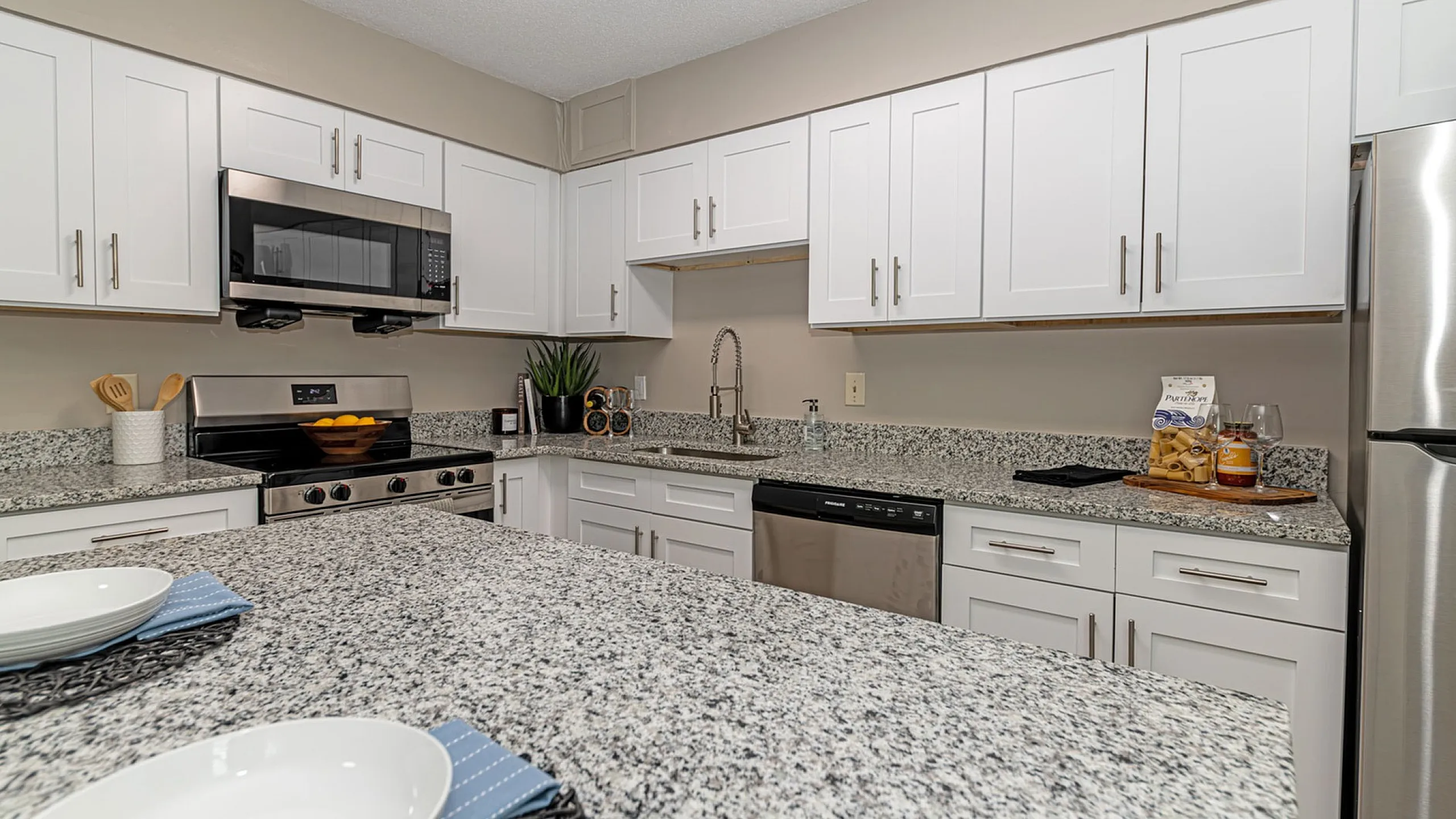 Elegant kitchen featuring modern stainless steel appliances, granite countertops, and sleek white cabinetry.