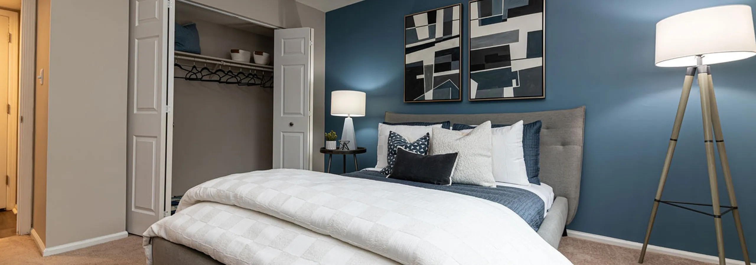 Elegant bedroom with a cozy king-sized bed, stylish blue accent wall, and chic modern decor showcasing ample closet space and soft ambient lighting.
