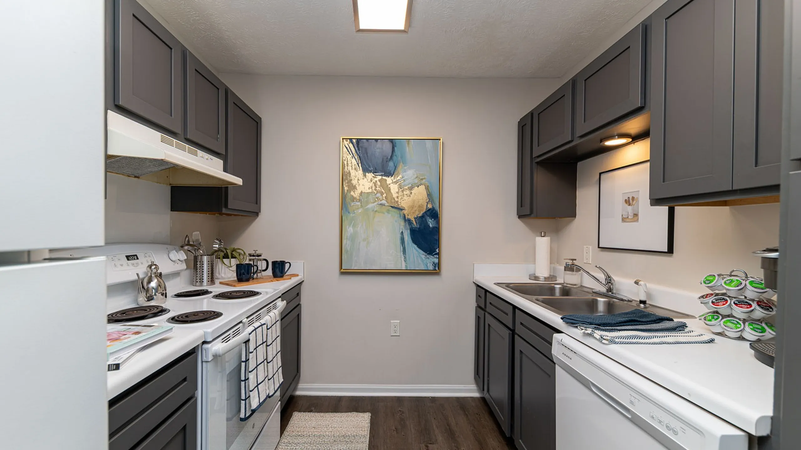 Chic modern kitchen featuring elegant dark cabinets, stainless steel appliances, and stylish artwork.