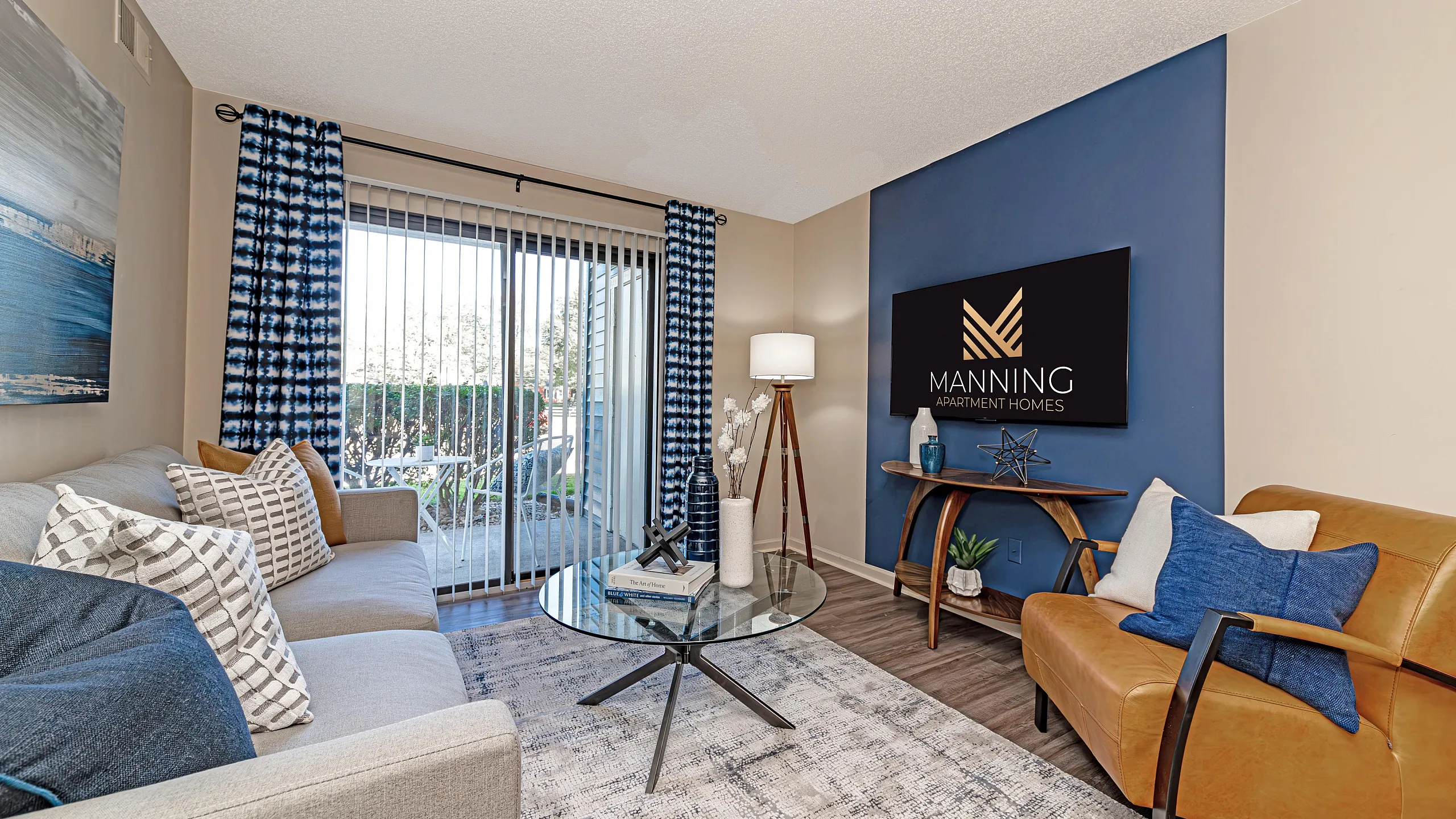 Elegant living room with a plush sofa, stylish armchair, and chic decor, featuring large sliding glass doors for ample natural light at Manning Apartment Homes.