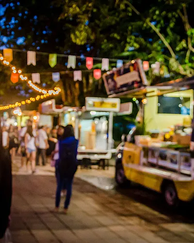 Vibrant evening market scene with colorful food trucks and festive lights creating a lively atmosphere.