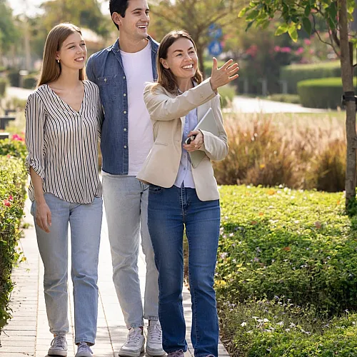 Happy group exploring a vibrant garden path in a modern residential complex on a sunny day.