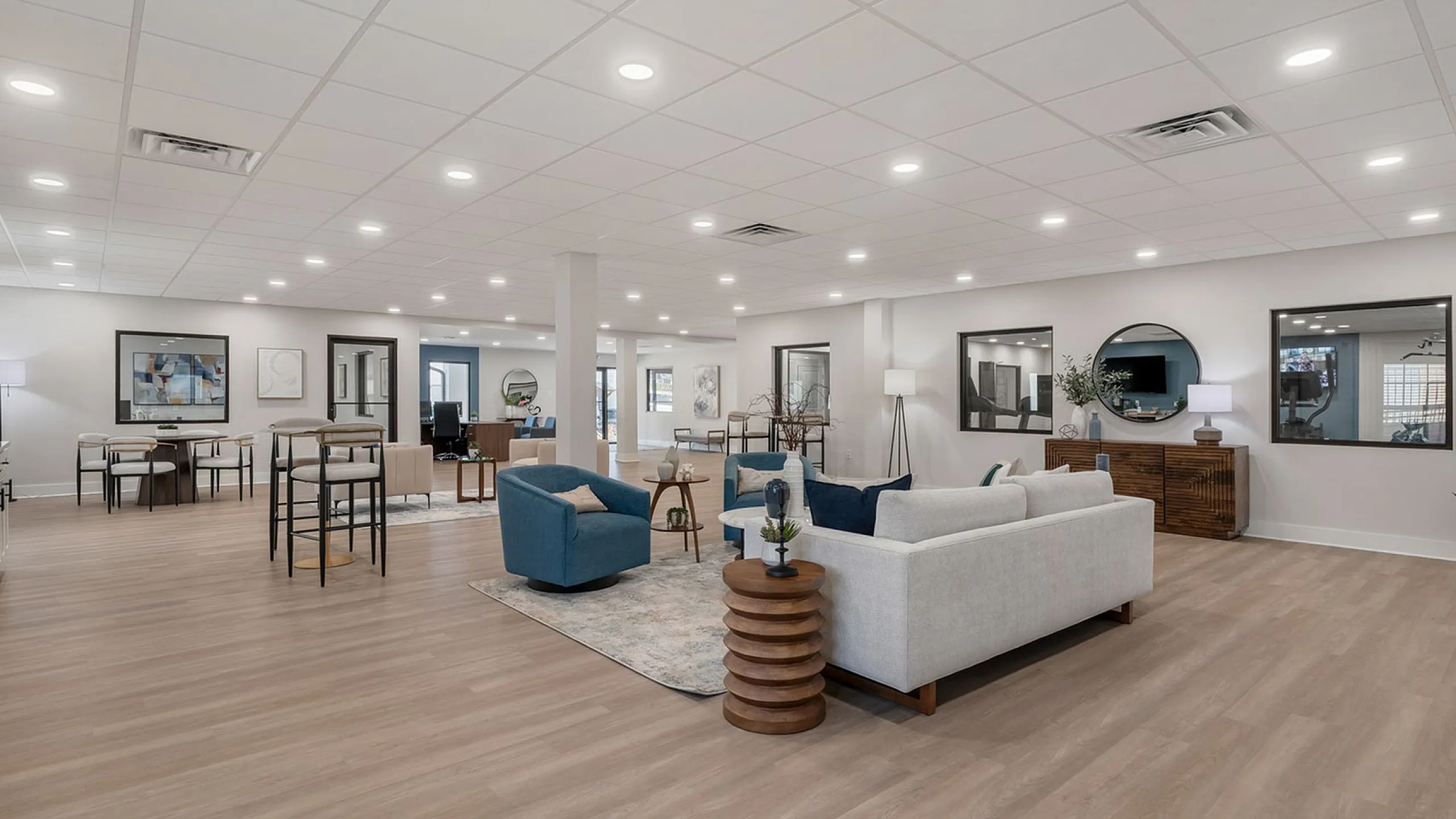 Elegant and spacious open-concept living area with modern furnishings, ample lighting, and sleek wooden flooring.