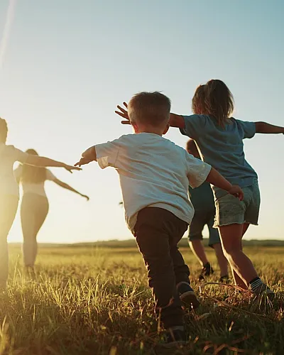 Joyful children running across a sunlit meadow at sunset, arms outstretched, capturing the essence of childhood freedom and happiness.