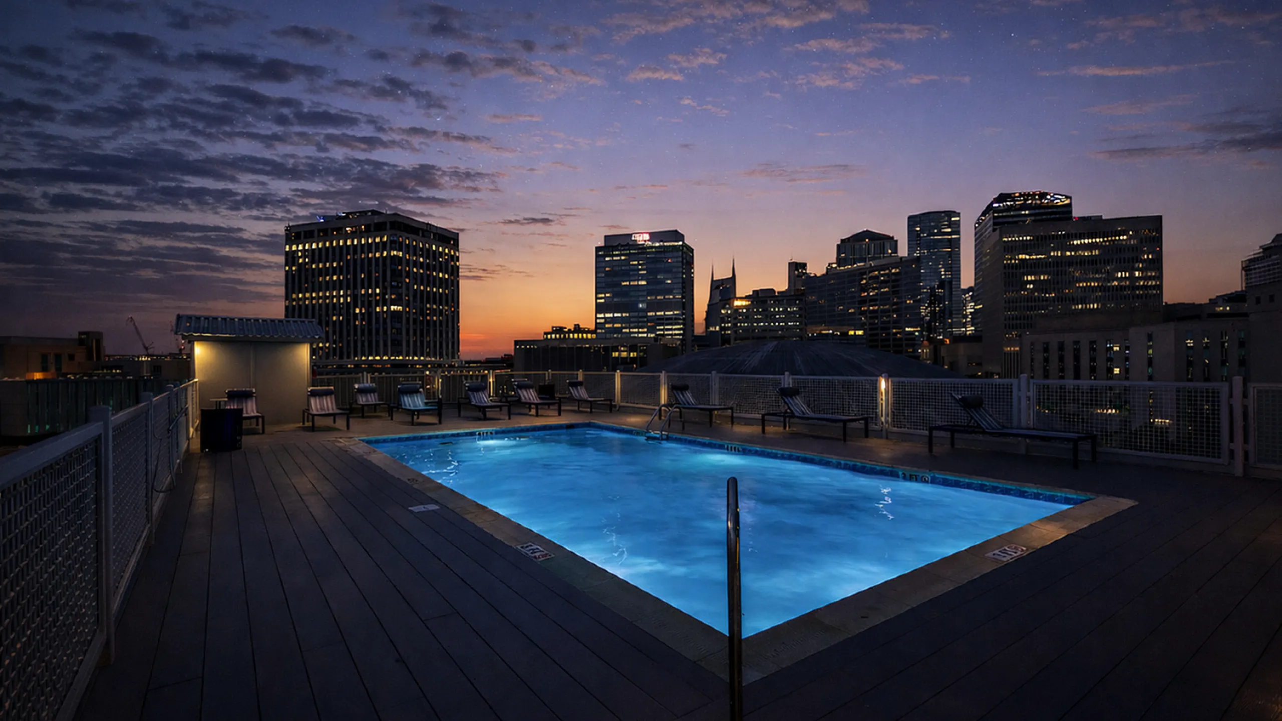 Luxurious rooftop pool with mesmerizing city skyline view at sunset.