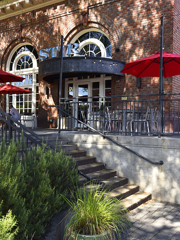 Charming outdoor patio with vibrant red umbrellas and elegant brick building, perfect for relaxing dining experience.