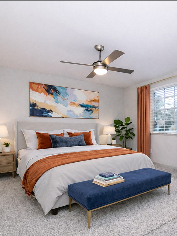 Elegant bedroom with a plush bed, vibrant orange accents, and stylish artwork, creating a cozy and inviting atmosphere.