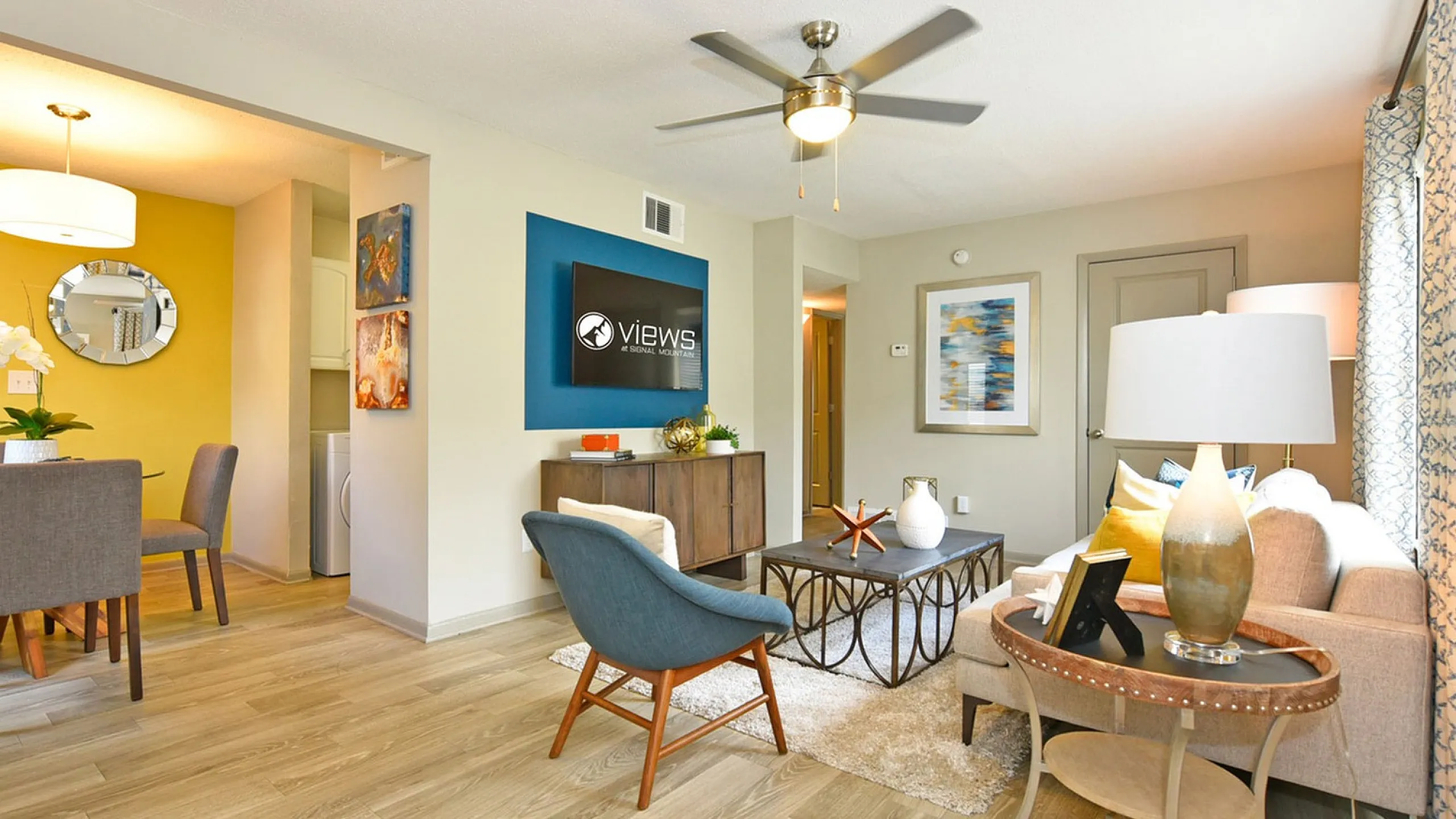 Modern living and dining area with elegant decor, featuring a ceiling fan, comfortable seating, and a charming dining nook with stylish lighting.