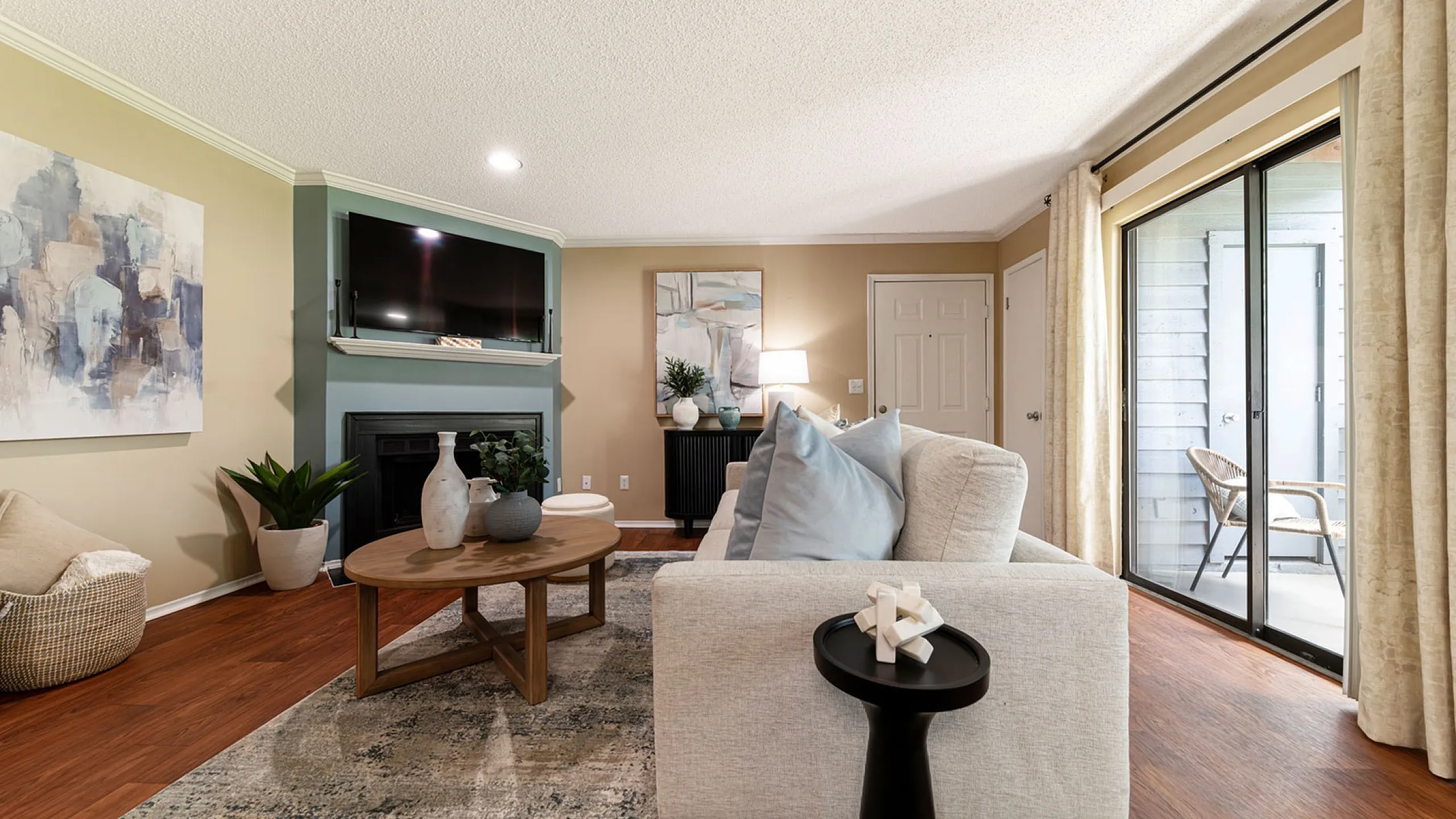 Inviting living room with modern decor, featuring a cozy sofa, sleek fireplace, and large sliding glass doors opening to a sunlit patio.