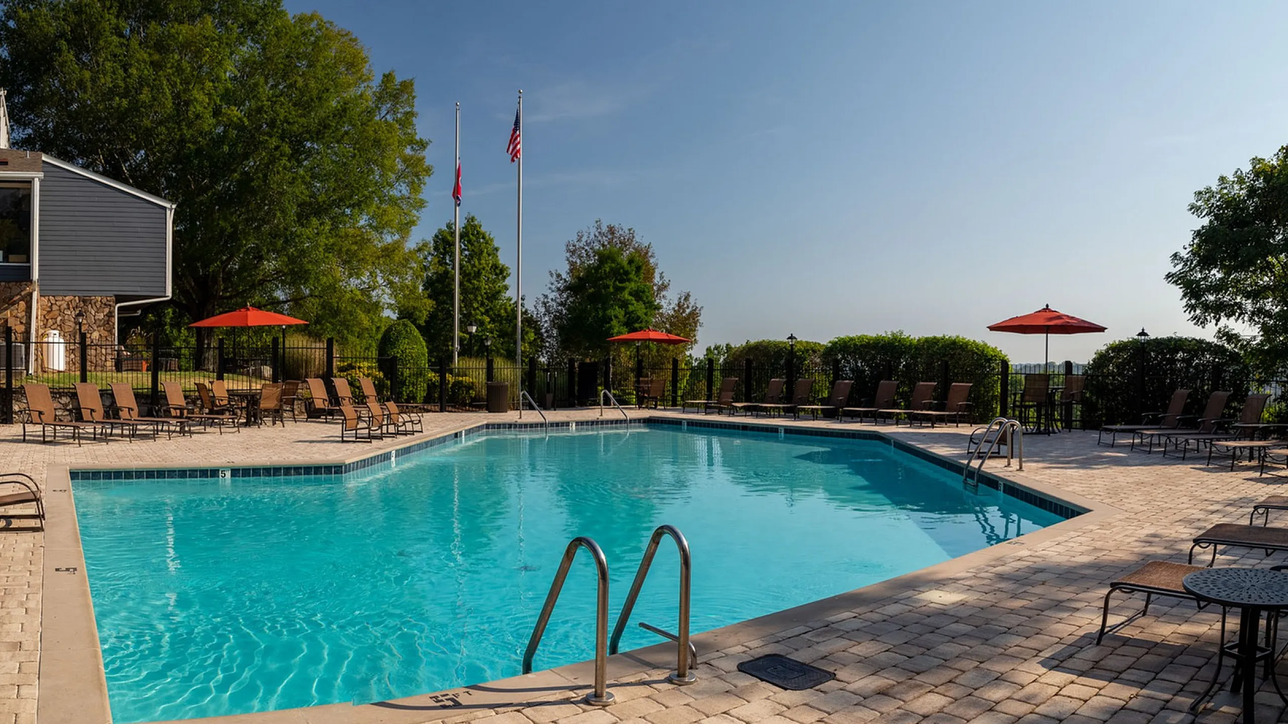 Inviting outdoor pool area with lounge chairs and red umbrellas, perfect for relaxation and soaking in the sun.