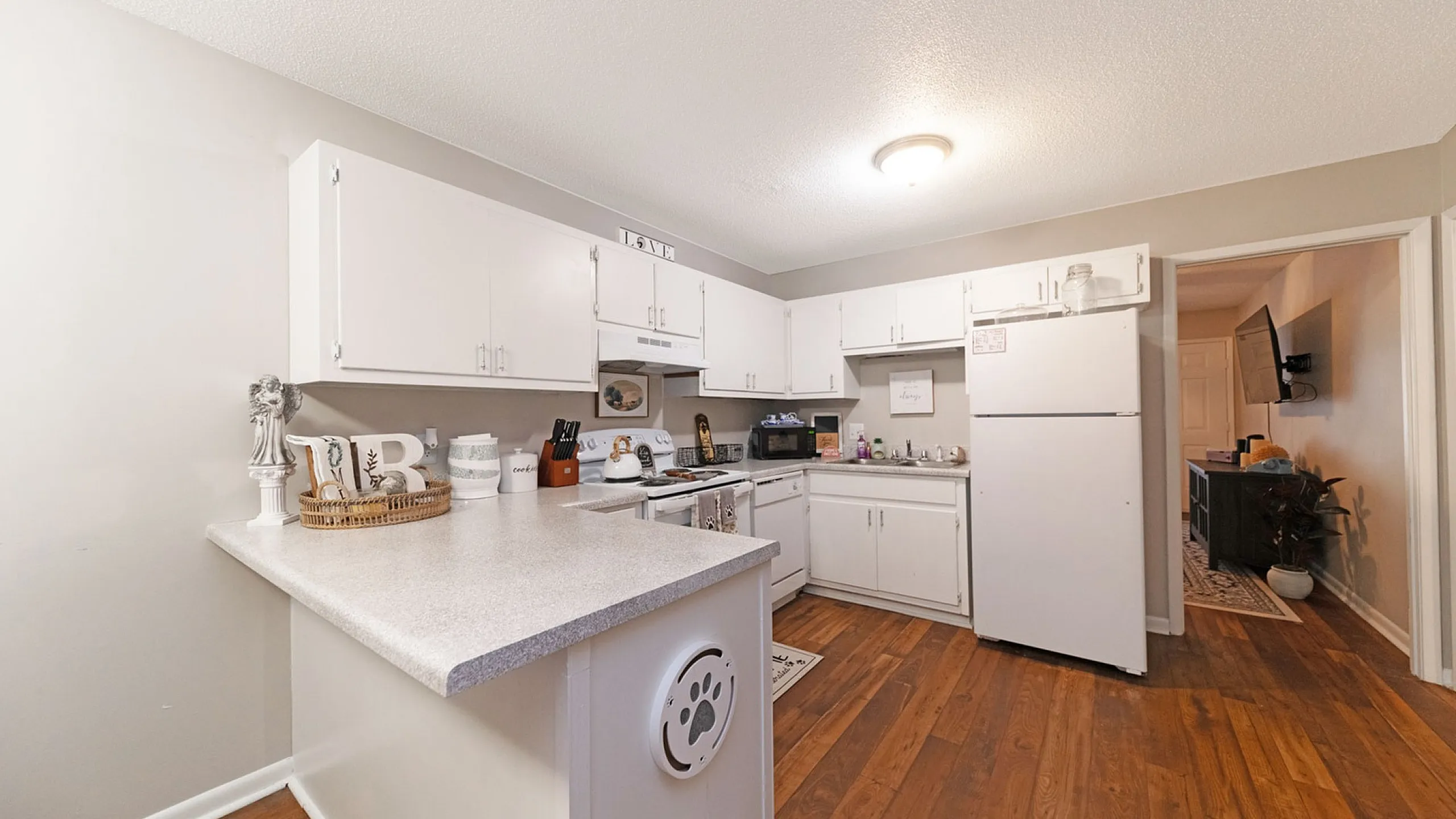 Charming modern kitchen with white cabinetry, sleek countertops, and warm wood flooring, perfect for culinary enthusiasts.