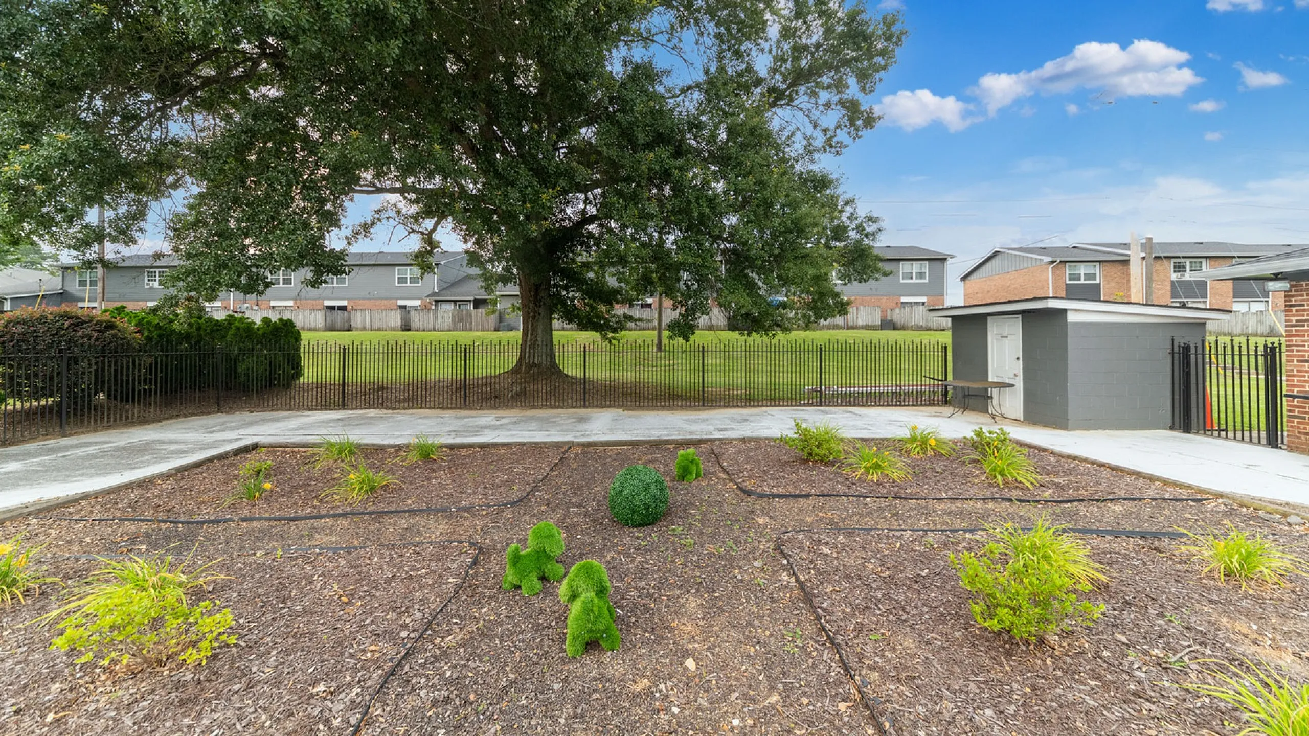 Charming outdoor space featuring a large tree, meticulously maintained garden, and vibrant green landscaping, ideal for relaxation and gatherings.